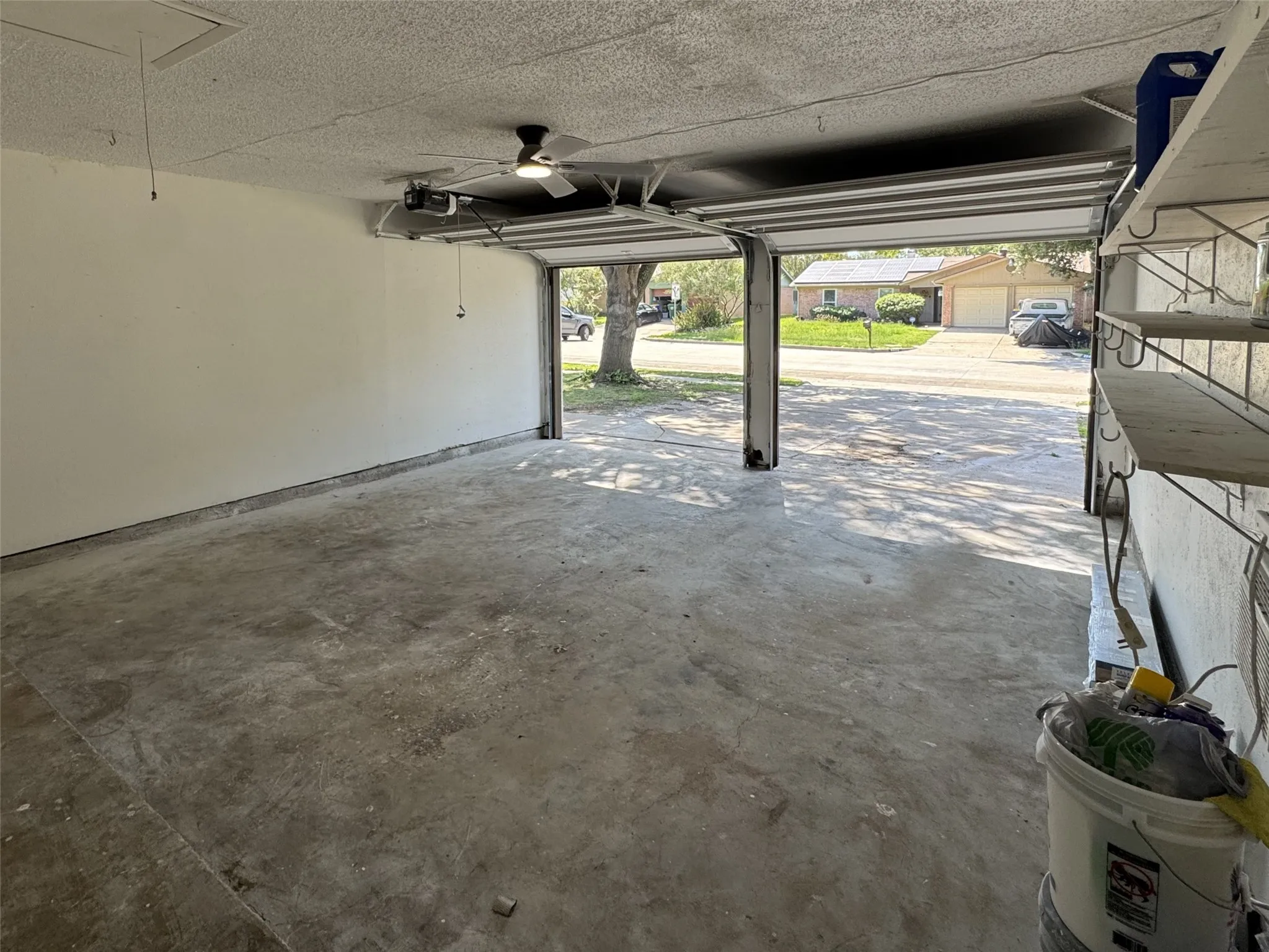 Garage space featuring a concrete floor, white painted walls, and an overhead ceiling fan