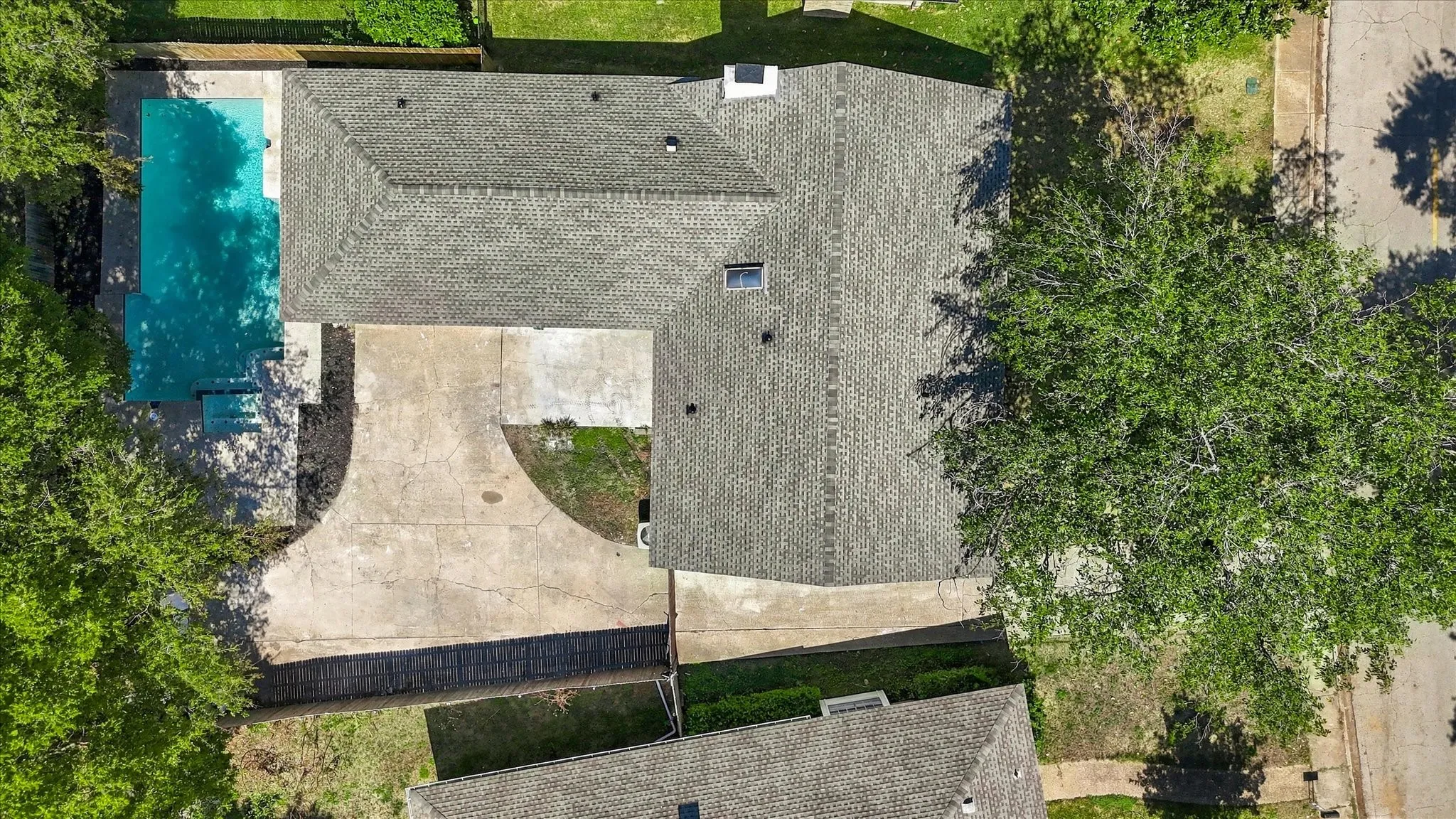 Expansive backyard with a rectangular swimming pool, concrete patio, and a wood privacy fence