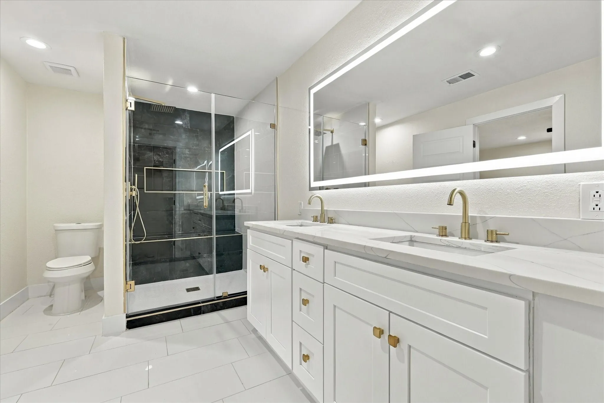 Walk-in shower with gold-finish fixtures, a built-in bench, a recessed niche, and contrasting tile finishes