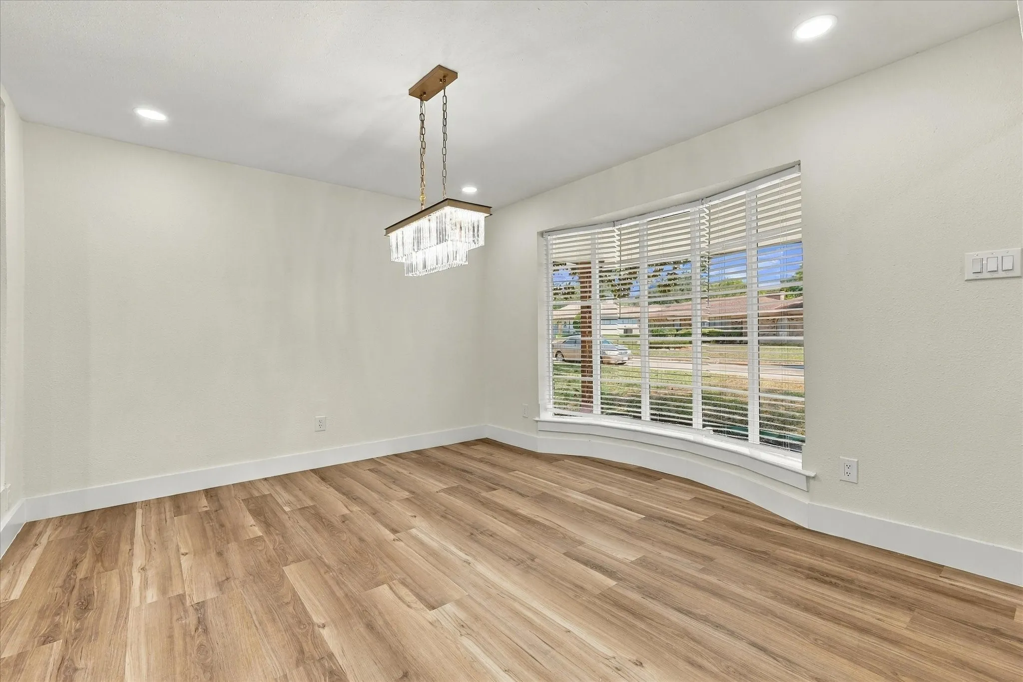 Wood-finish flooring throughout, white cabinetry with gold-tone hardware, white subway tile backsplash, stainless steel dishwasher, and recessed ceiling lighting