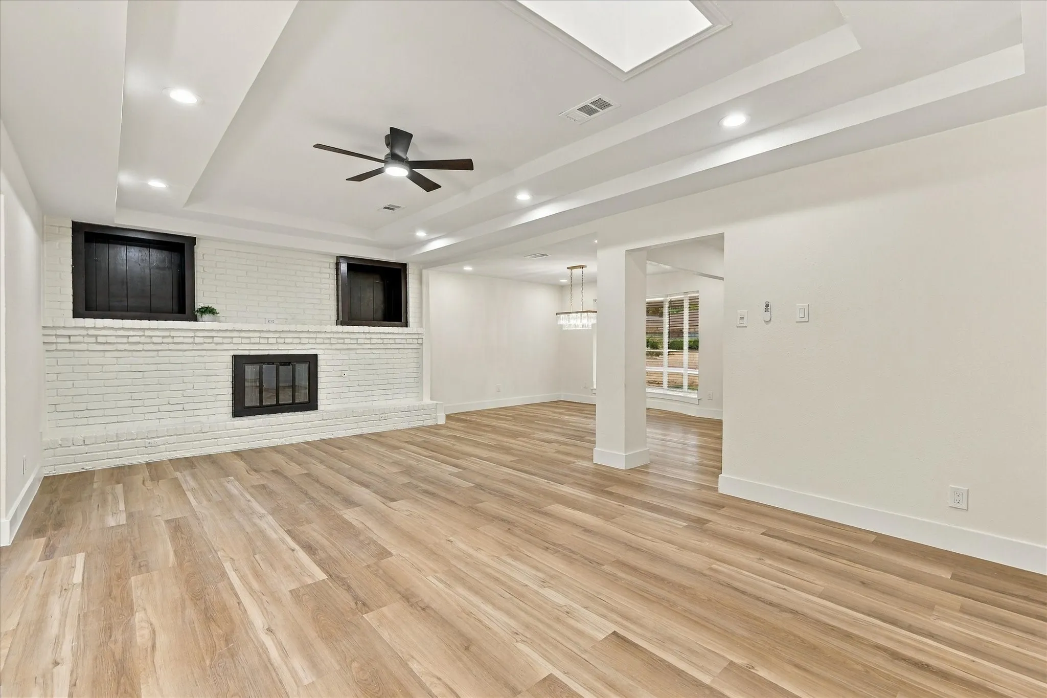 Kitchen featuring white shaker cabinetry, gold-tone hardware, a stainless steel dishwasher, a black range, and wood-finish flooring