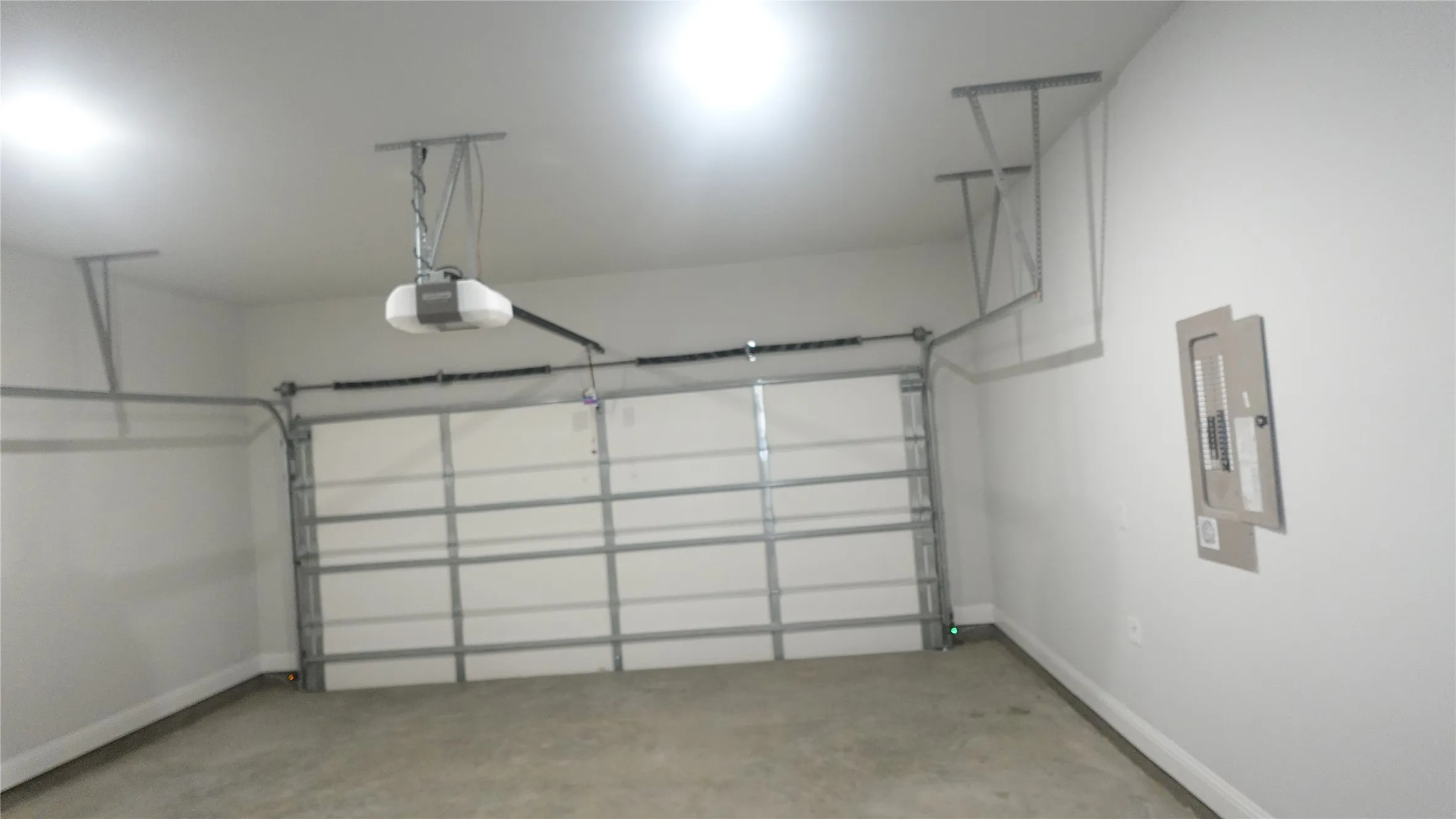Garage featuring a concrete floor, white walls, and an automatic garage door opener