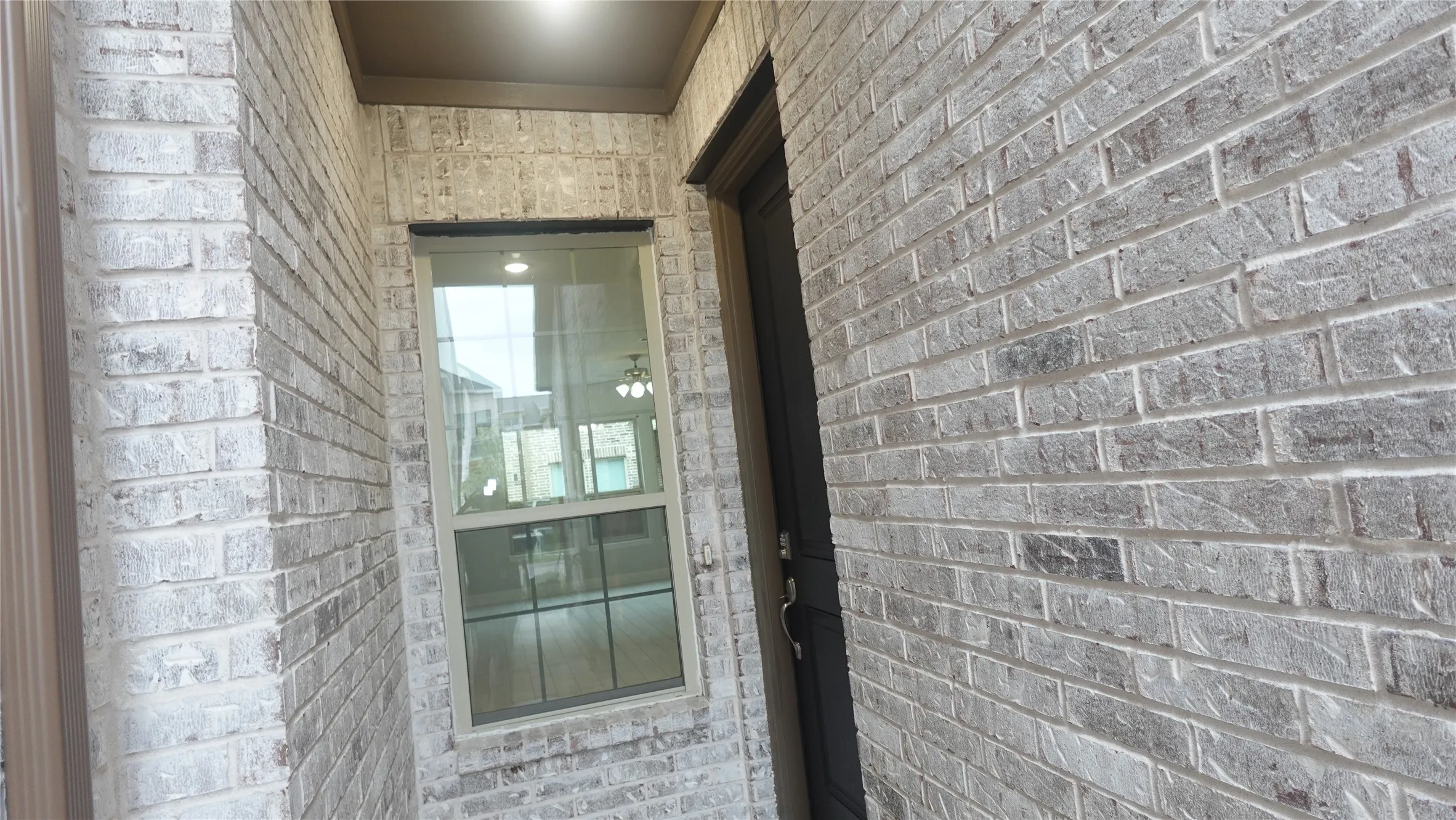 Brick exterior with a window featuring grilles and a dark-framed entry door