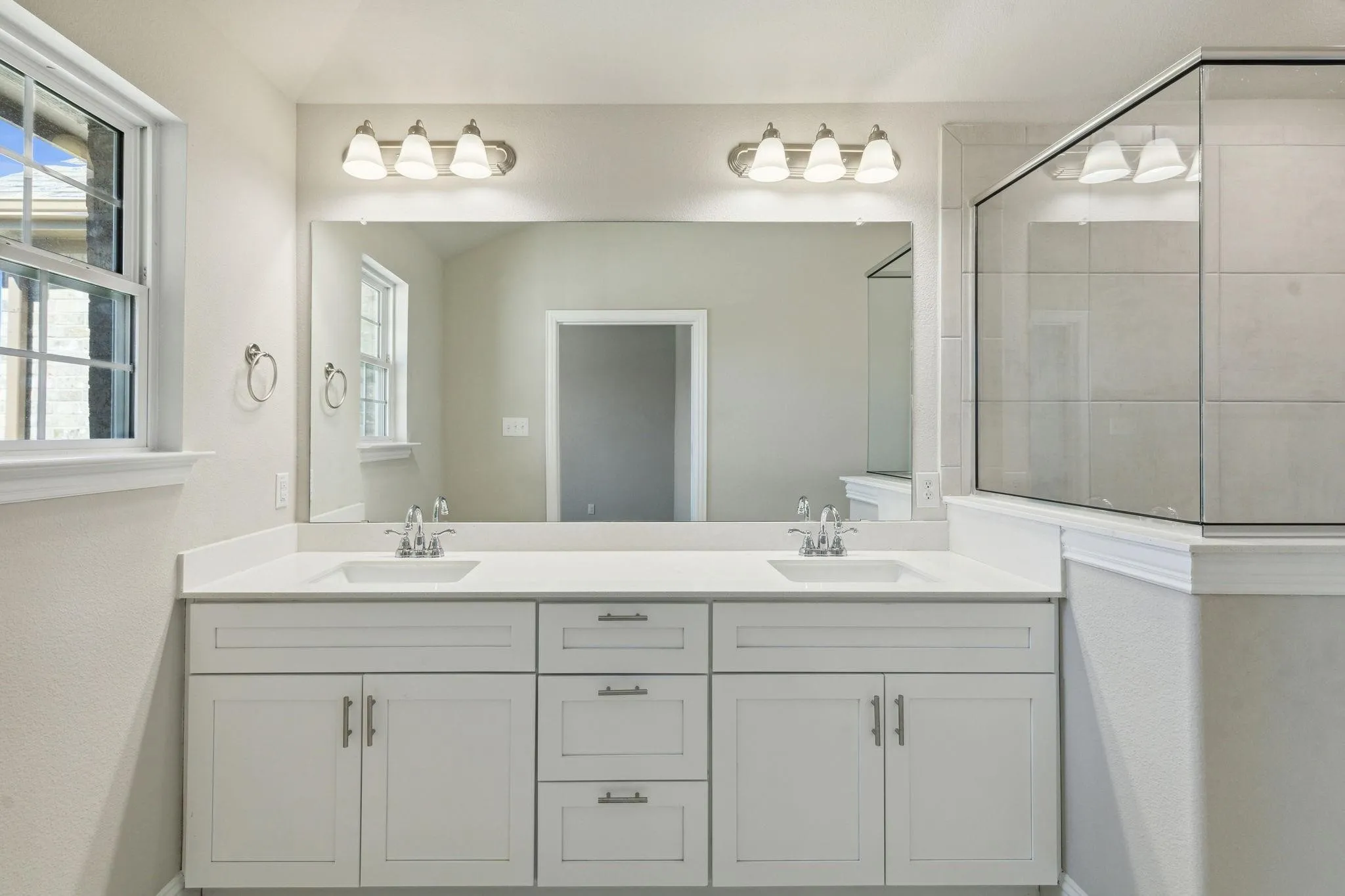 Dual vanity with white cabinetry, integrated sinks, and polished chrome fixtures