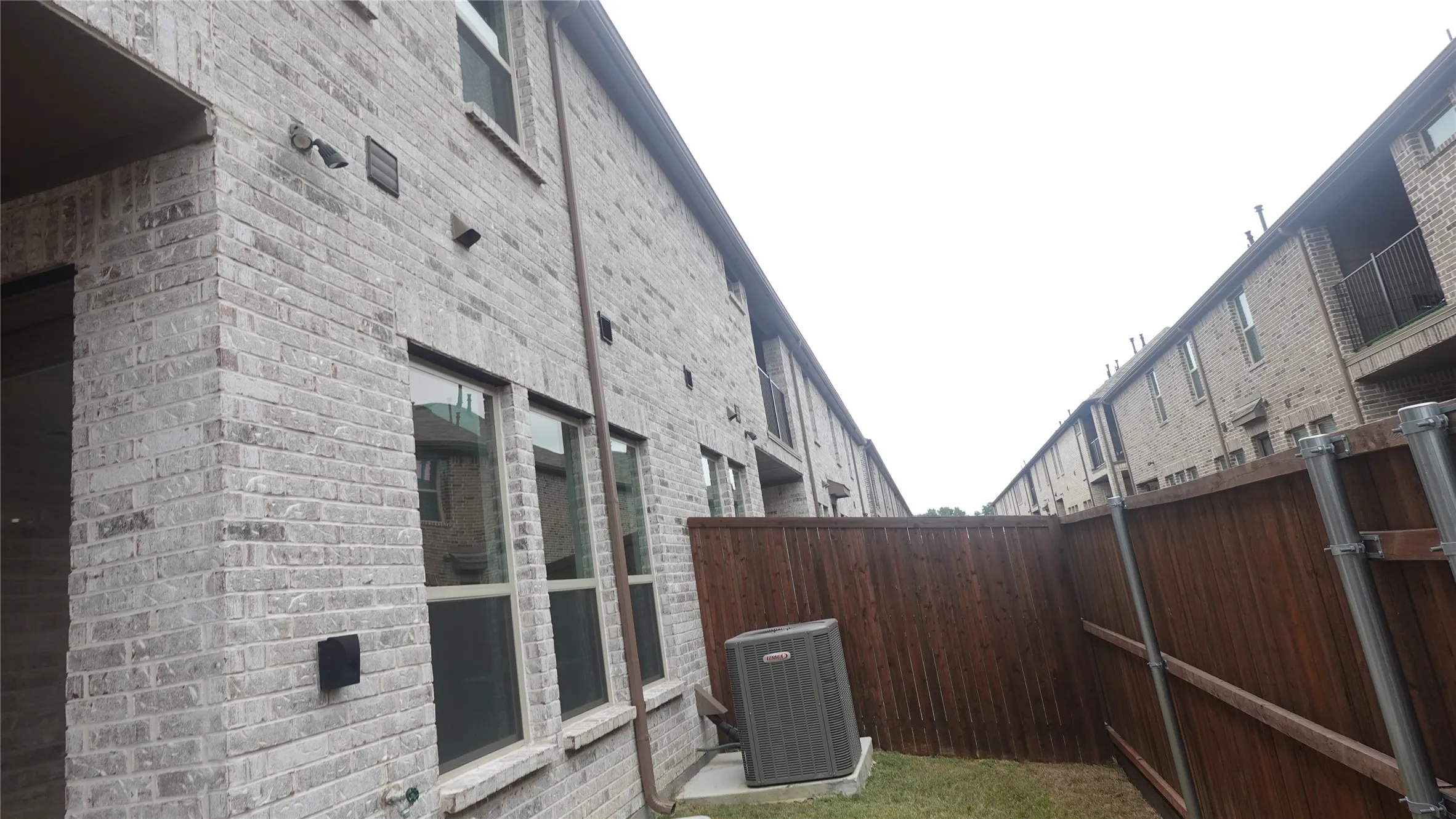 Brick exterior with multiple windows and a wood fence