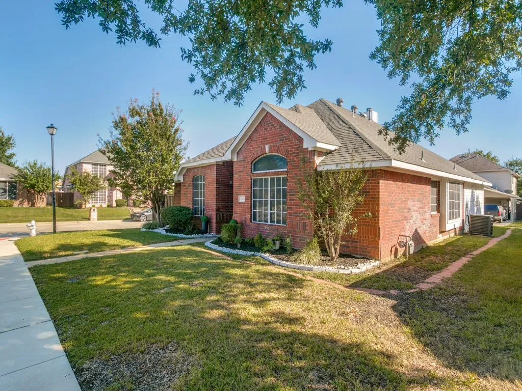 Brick exterior with an arched window, white trim accents, and a shingled roof
