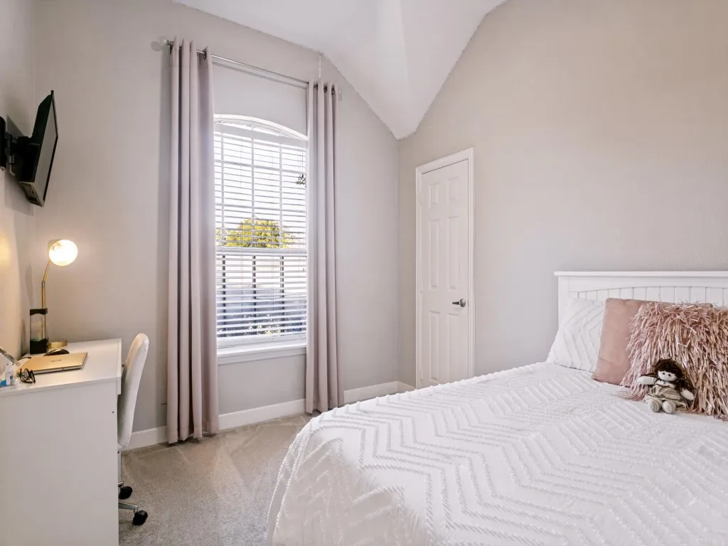 Vaulted ceiling, arched window with blinds, panel door, and soft grey wall tones
