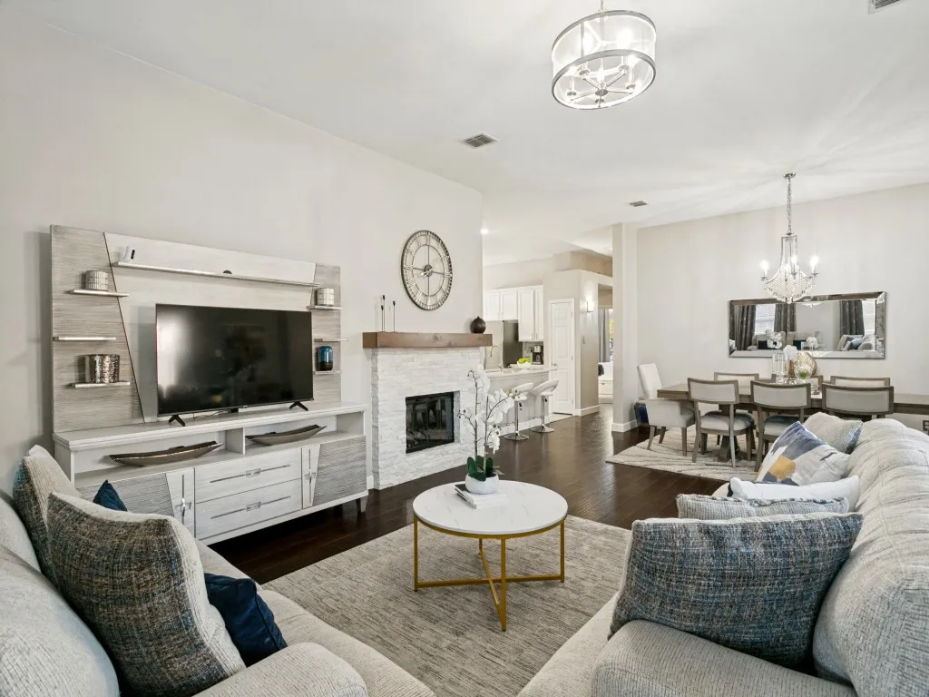 Open-concept living space featuring wood-finish flooring, a stacked stone fireplace with a wood mantel, and an attached dining area