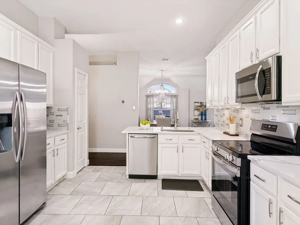 Kitchen featuring white cabinetry, light-toned tile flooring, stainless steel appliances, and a tiled backsplash
