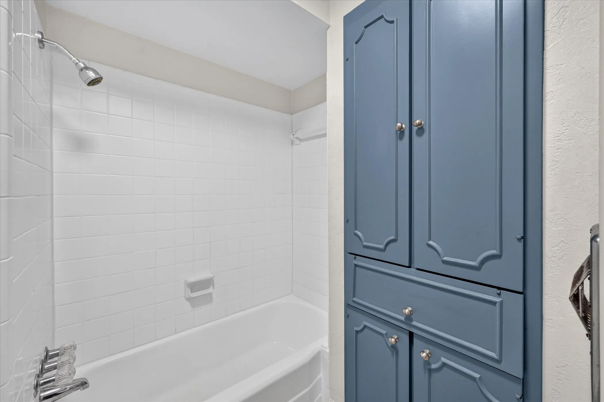 White subway tile shower surround with a built-in tub and chrome fixtures