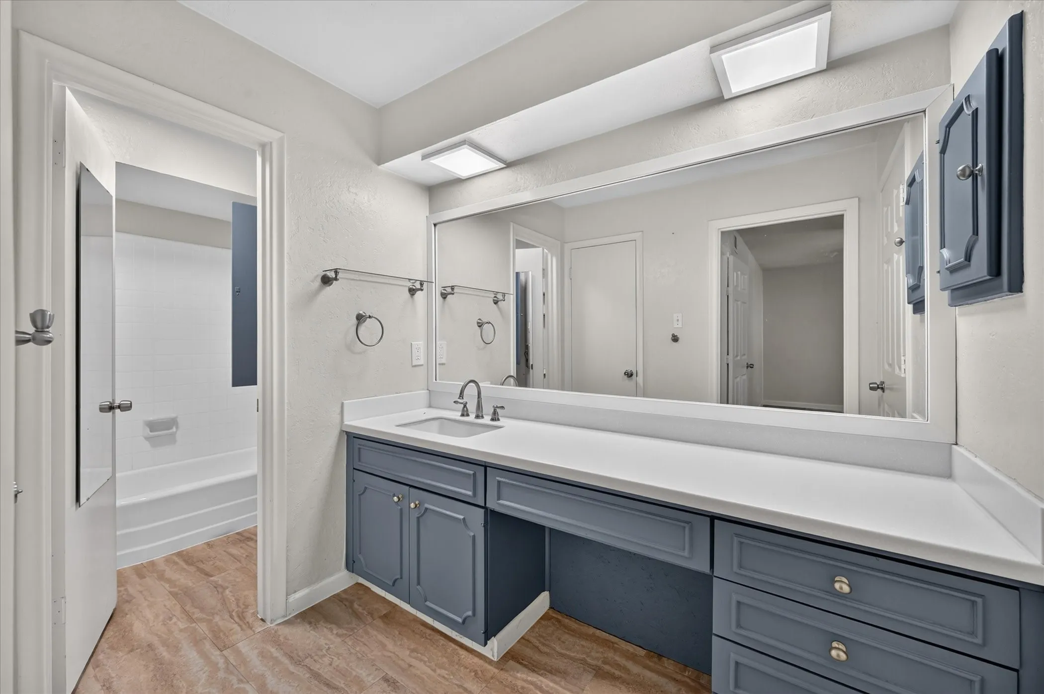 Vanity featuring a single basin, white countertop, and blue cabinetry, tile flooring