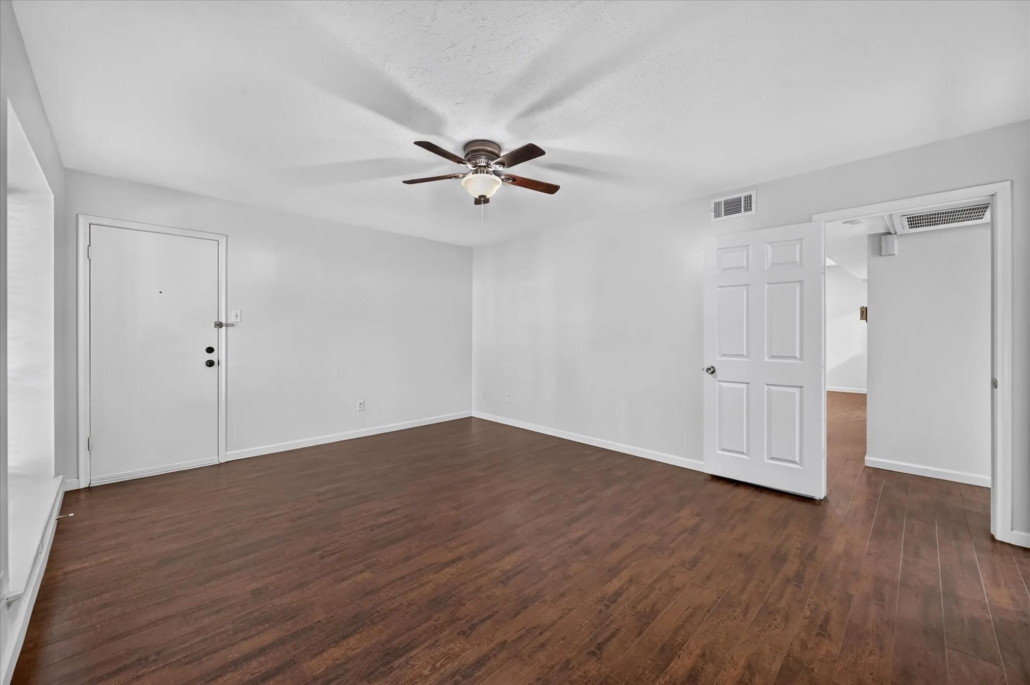 Spacious room featuring vinyl plank wood like finish flooring, a ceiling fan with integrated lighting, white walls, and white doors