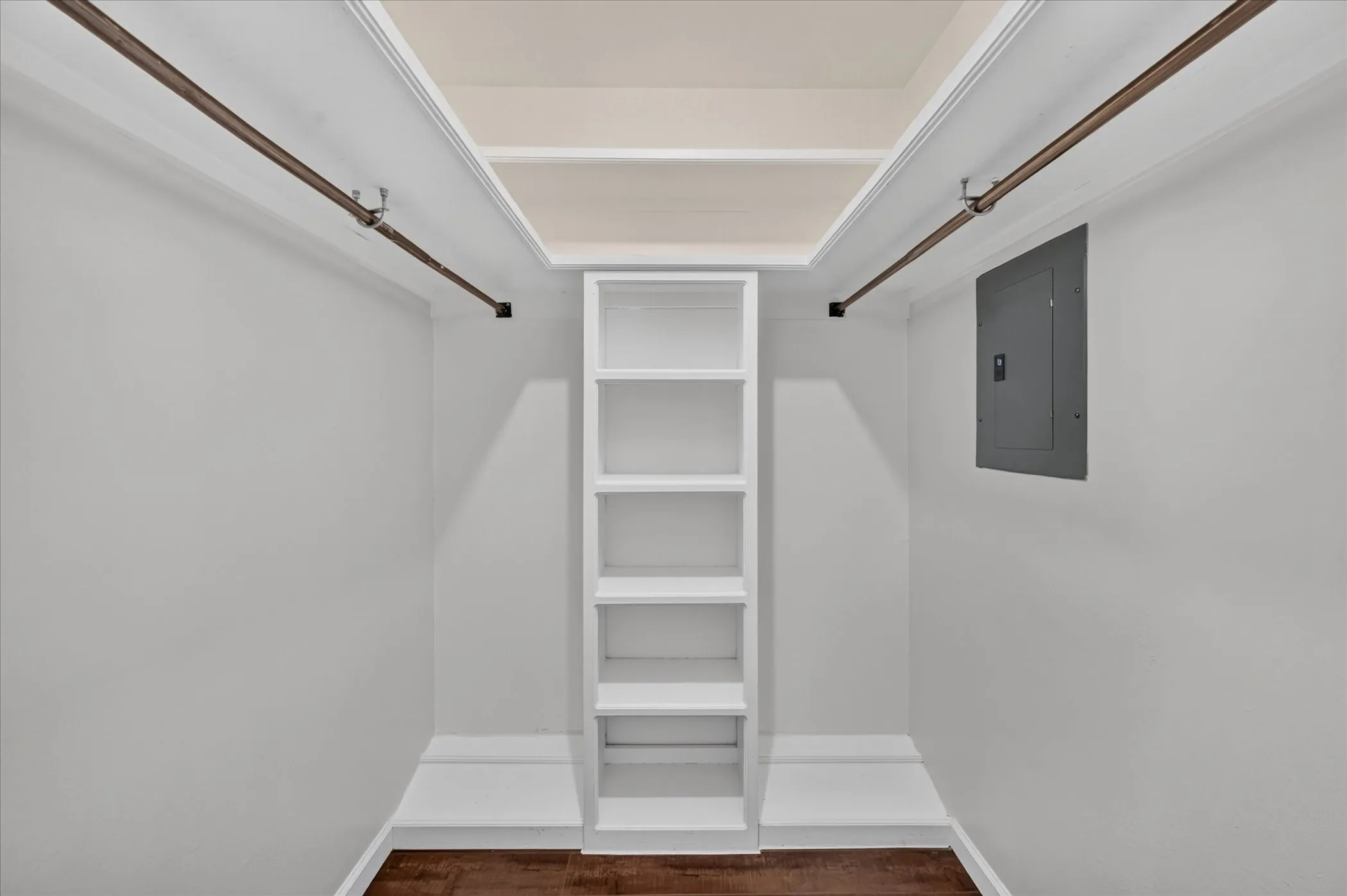 Closet space with built-in shelving, two clothing rods, and vinyl plank wood like finish flooring