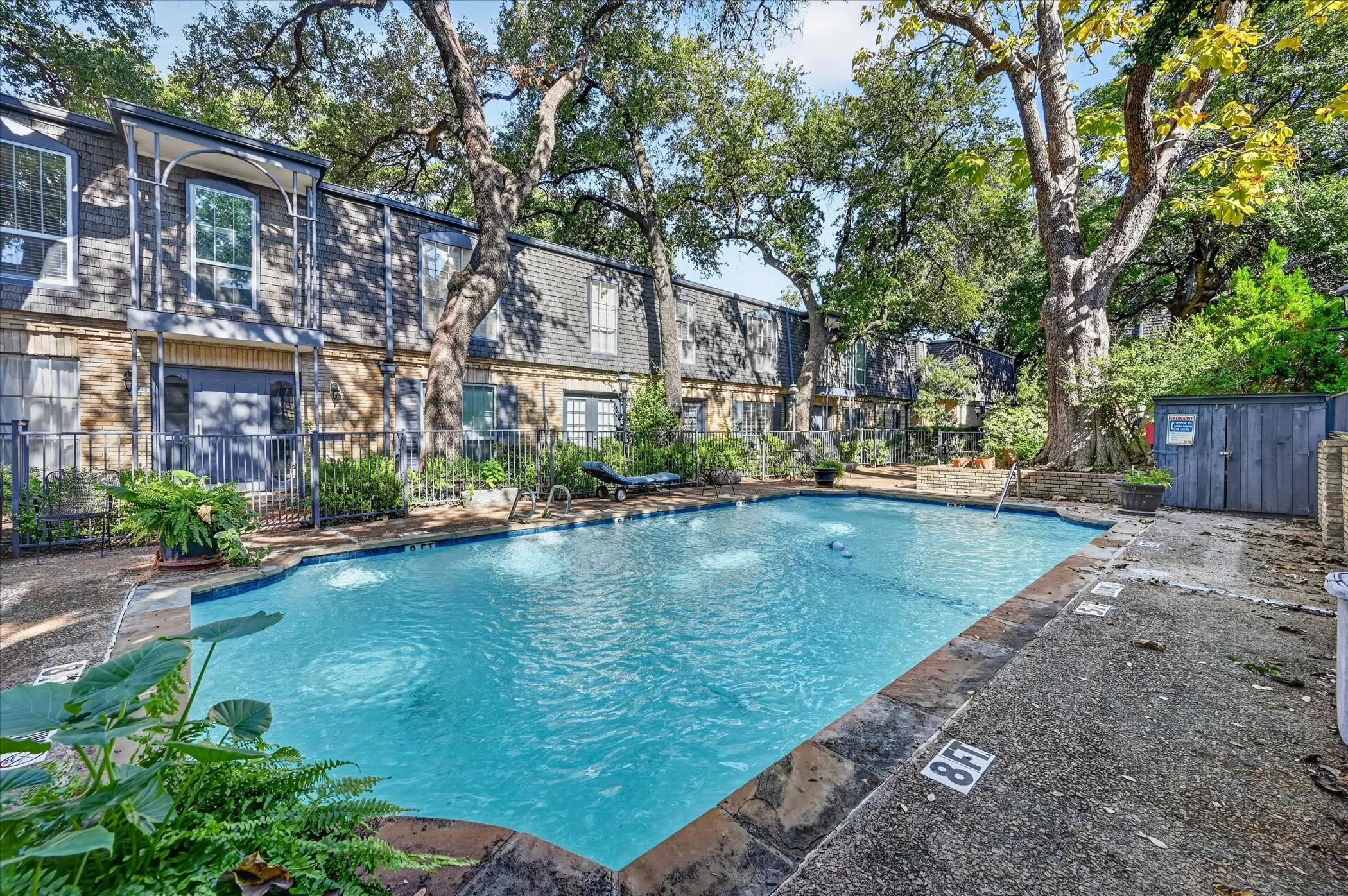 Community swimming pool with water features, surrounded by mature trees