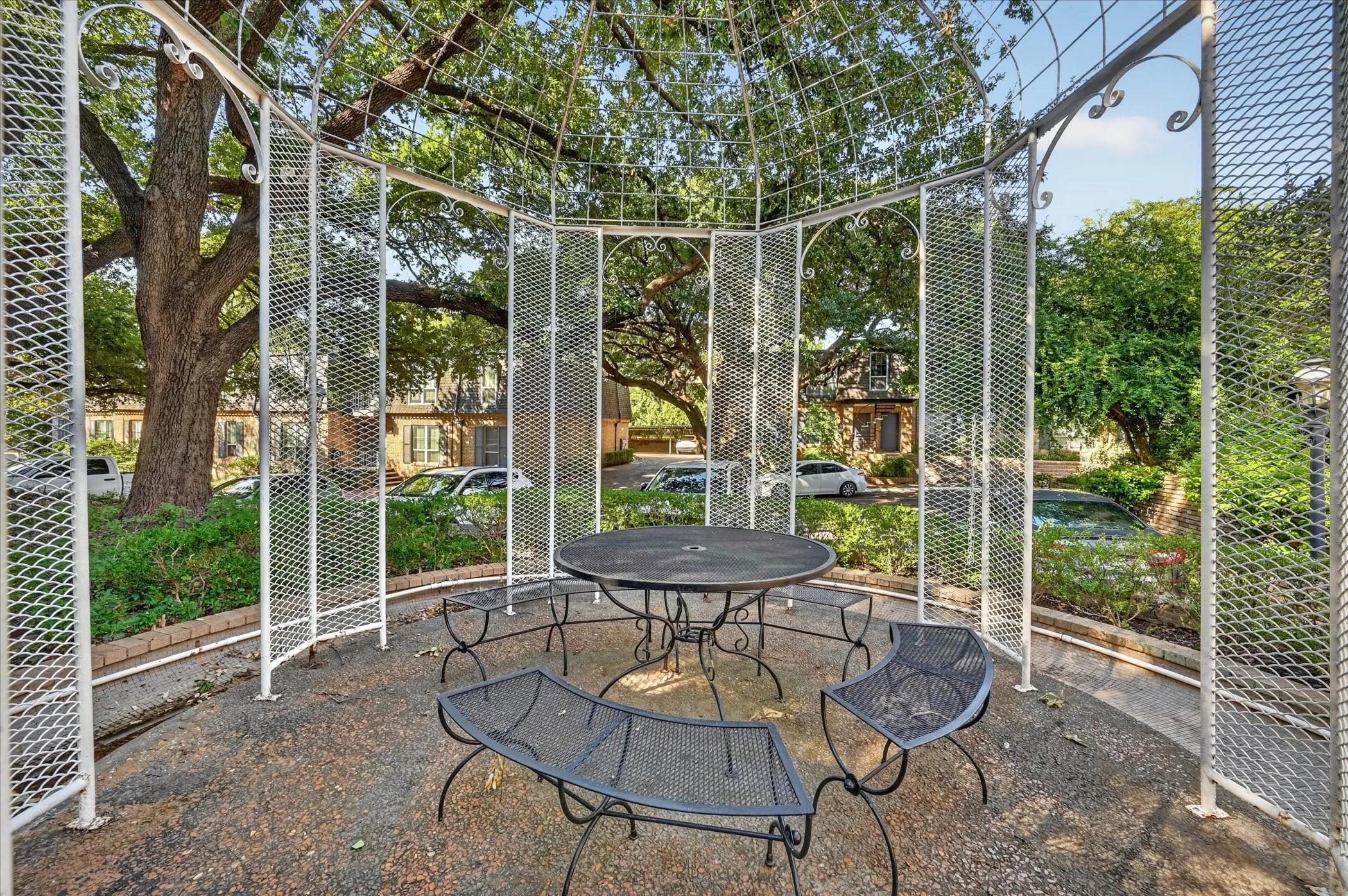 Gazebo with open lattice design, decorative metalwork, and concrete flooring