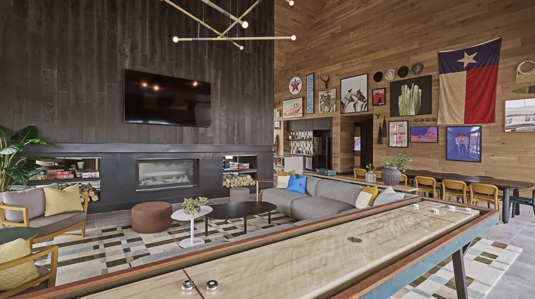Living room featuring a high ceiling, wood walls, a chandelier, a fireplace, and tile patterned floors