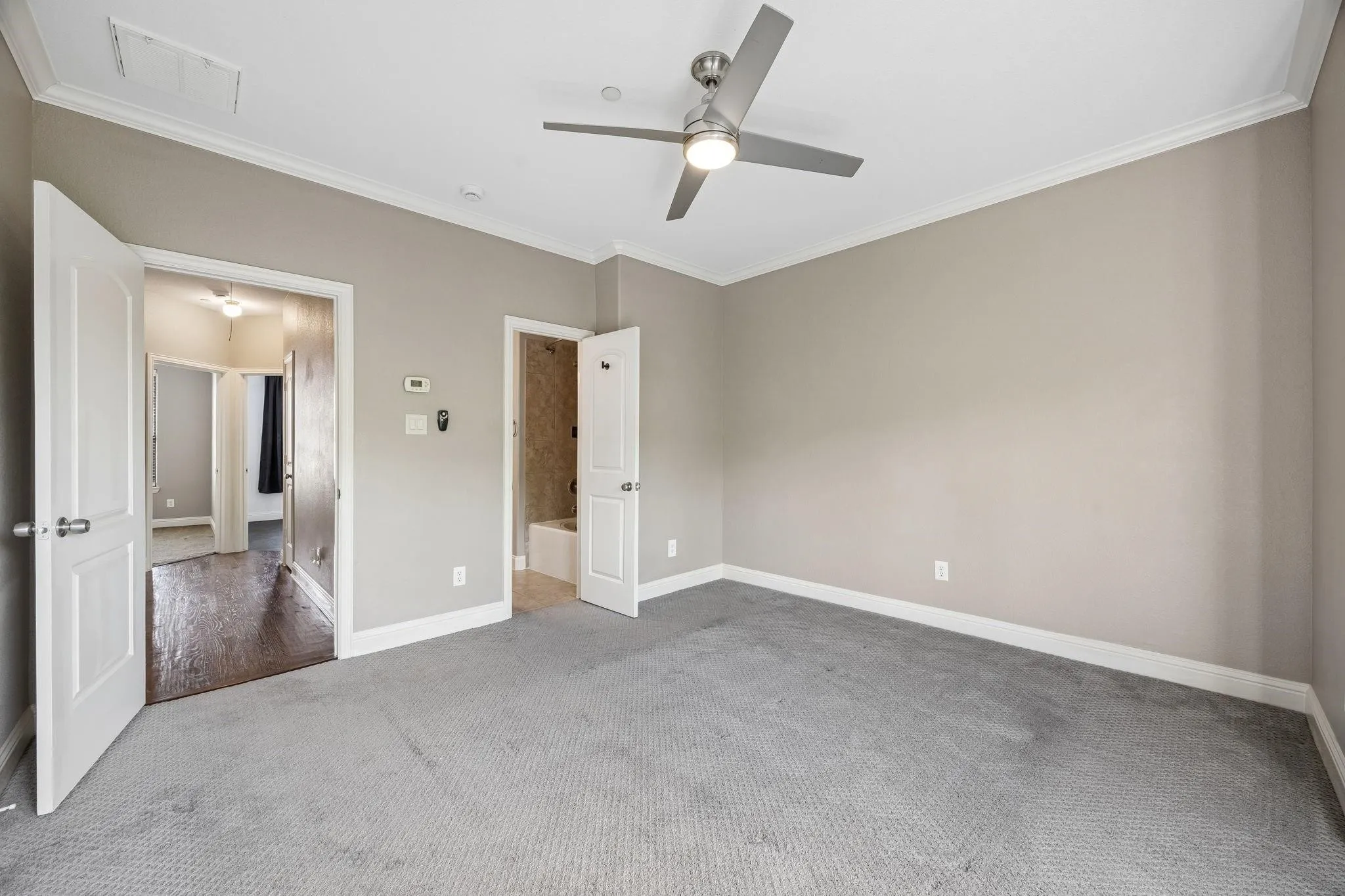 Spacious room featuring neutral-toned walls, crown molding, and a contemporary ceiling fan with integrated lighting