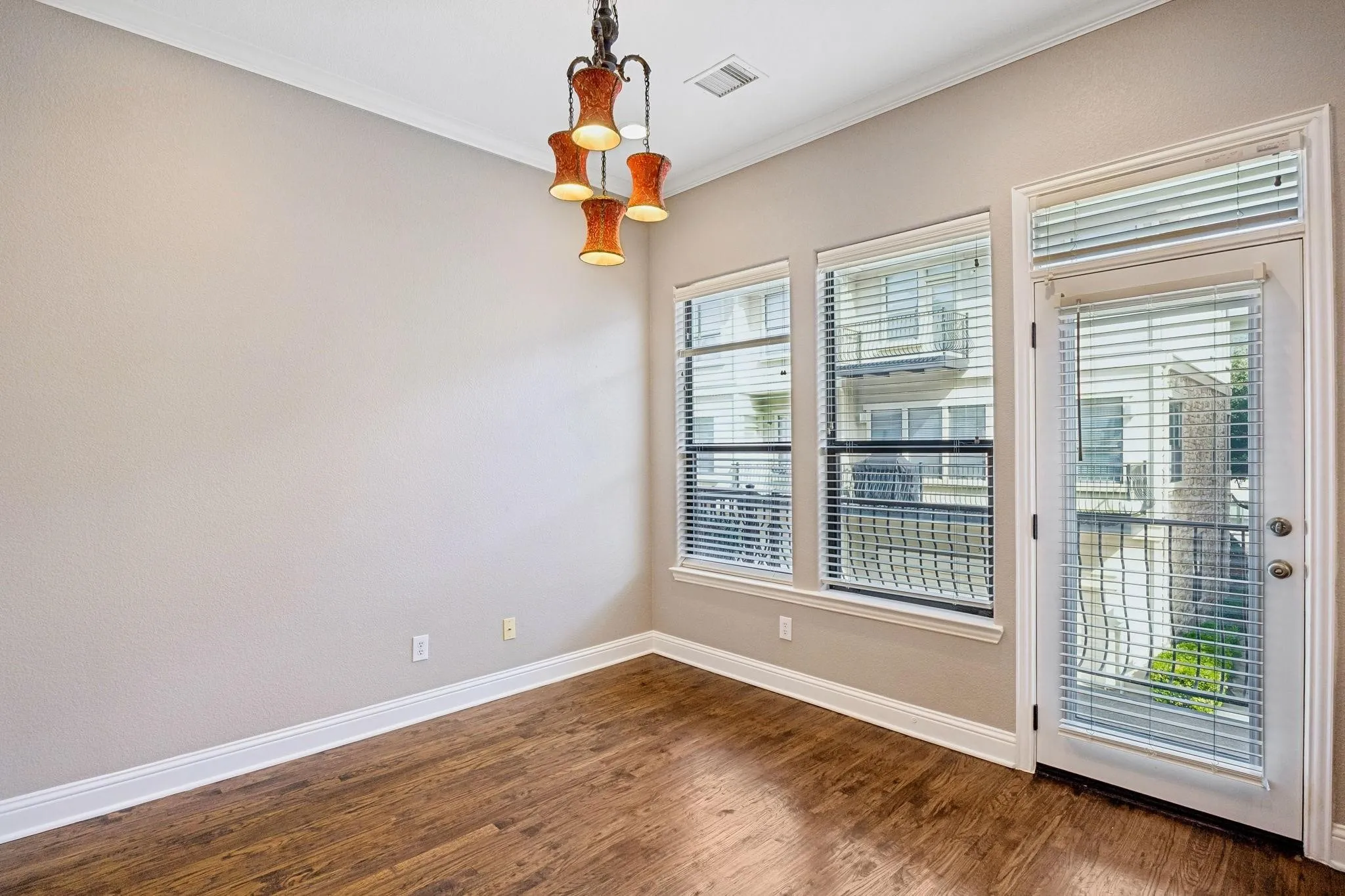 Wood-finish flooring, white trim, multiple windows, a glass-paned door, and a built-in light fixture