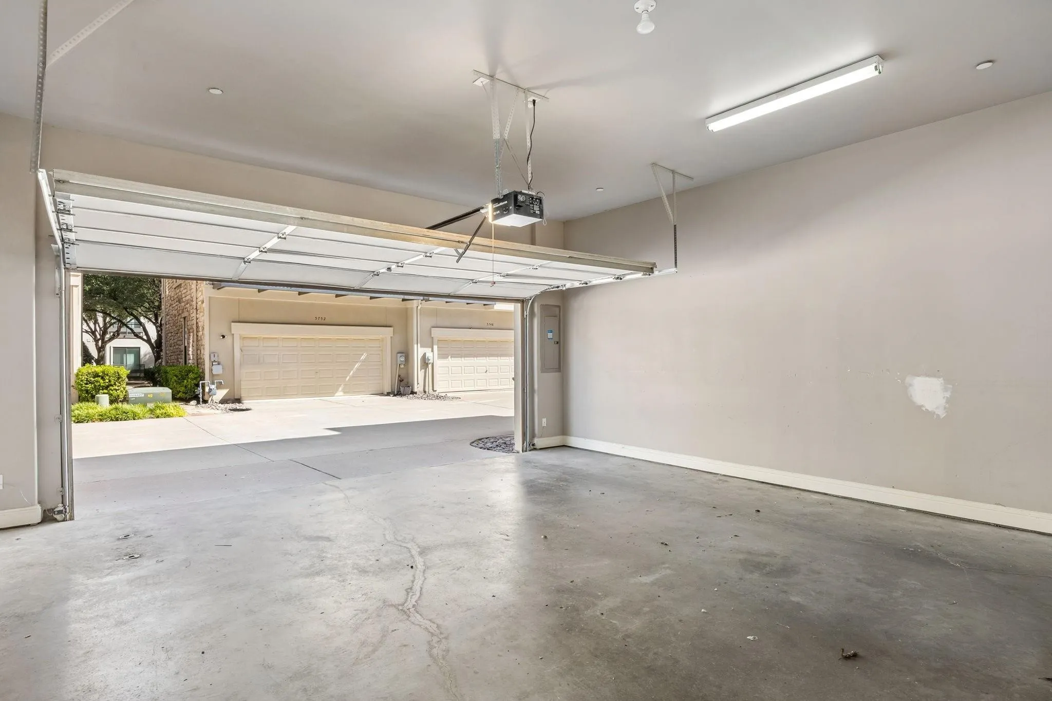 Attached garage with a concrete floor, automatic garage door opener, and fluorescent lighting