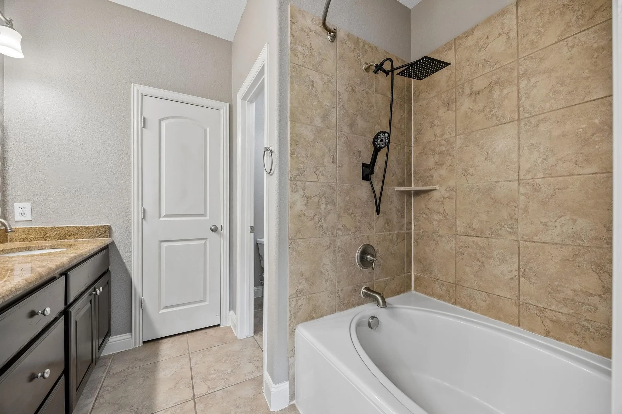 Bathtub with tiled surround, rain shower head, and handheld shower