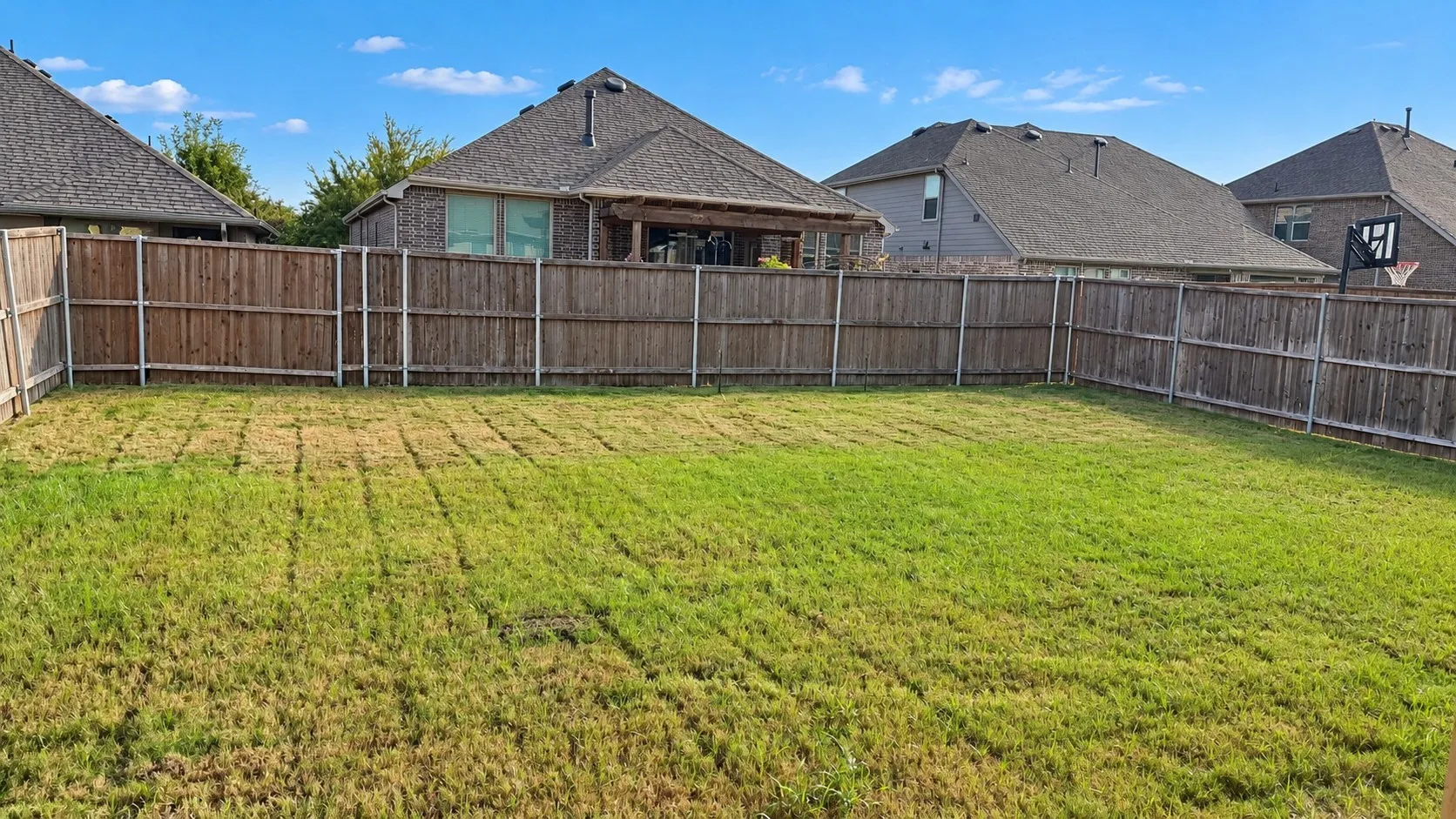 Expansive backyard featuring a wood fence perimeter and a manicured lawn