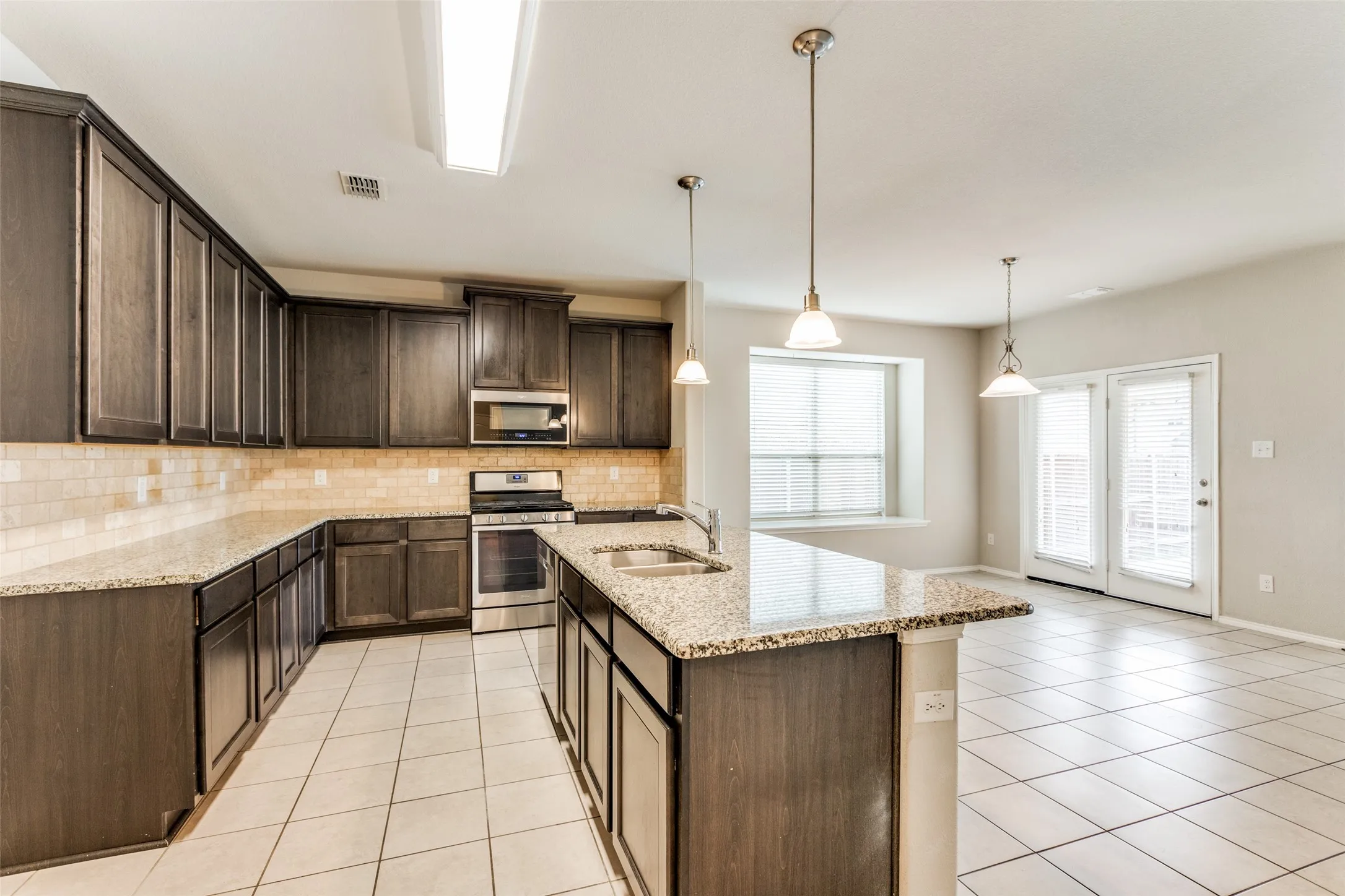 Kitchen featuring extensive dark-finish cabinetry, granite countertops, stainless steel appliances, and a tile backsplash