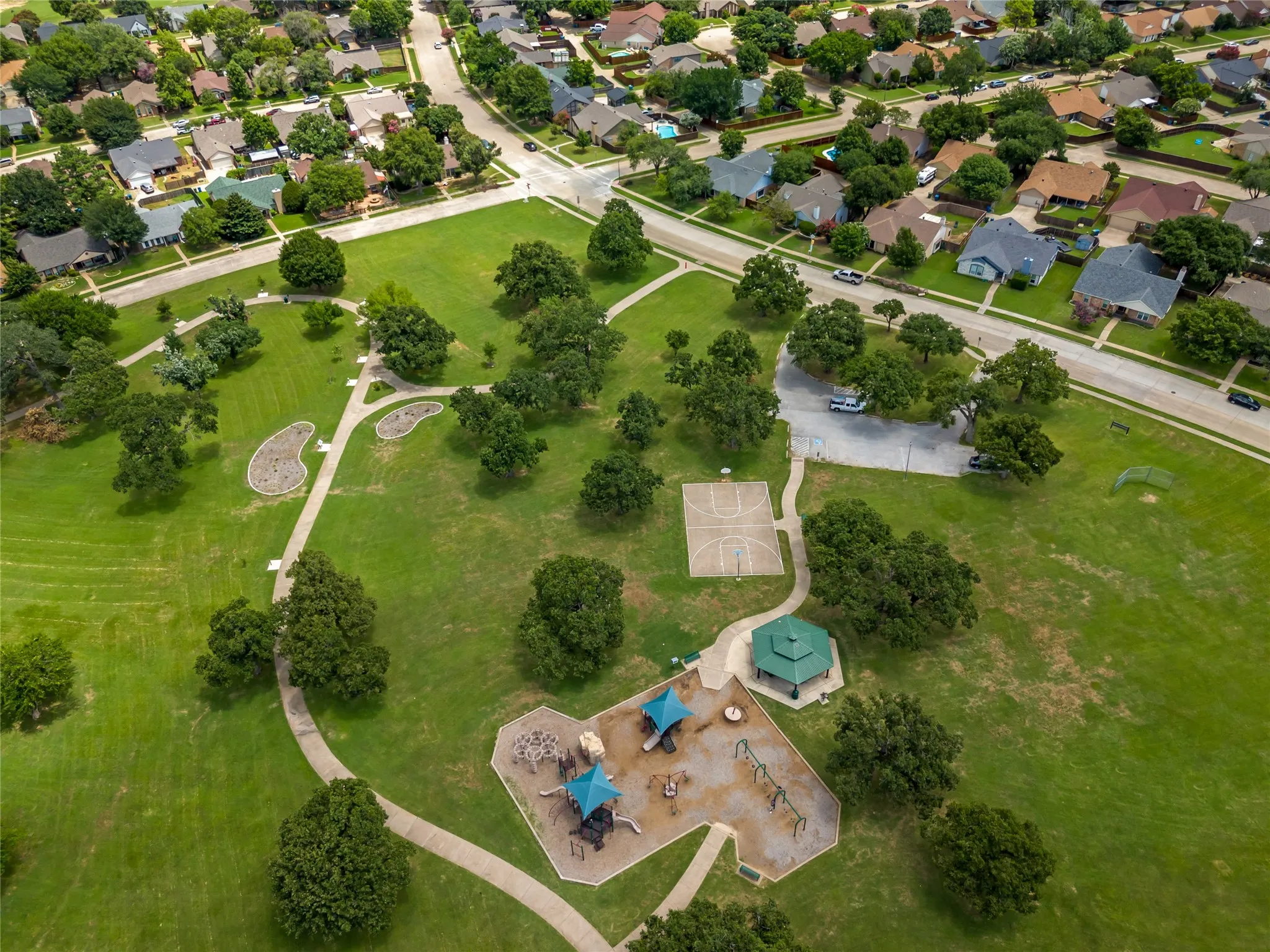 Across the street from park - expansive green space featuring a playground, basketball court, and walking paths