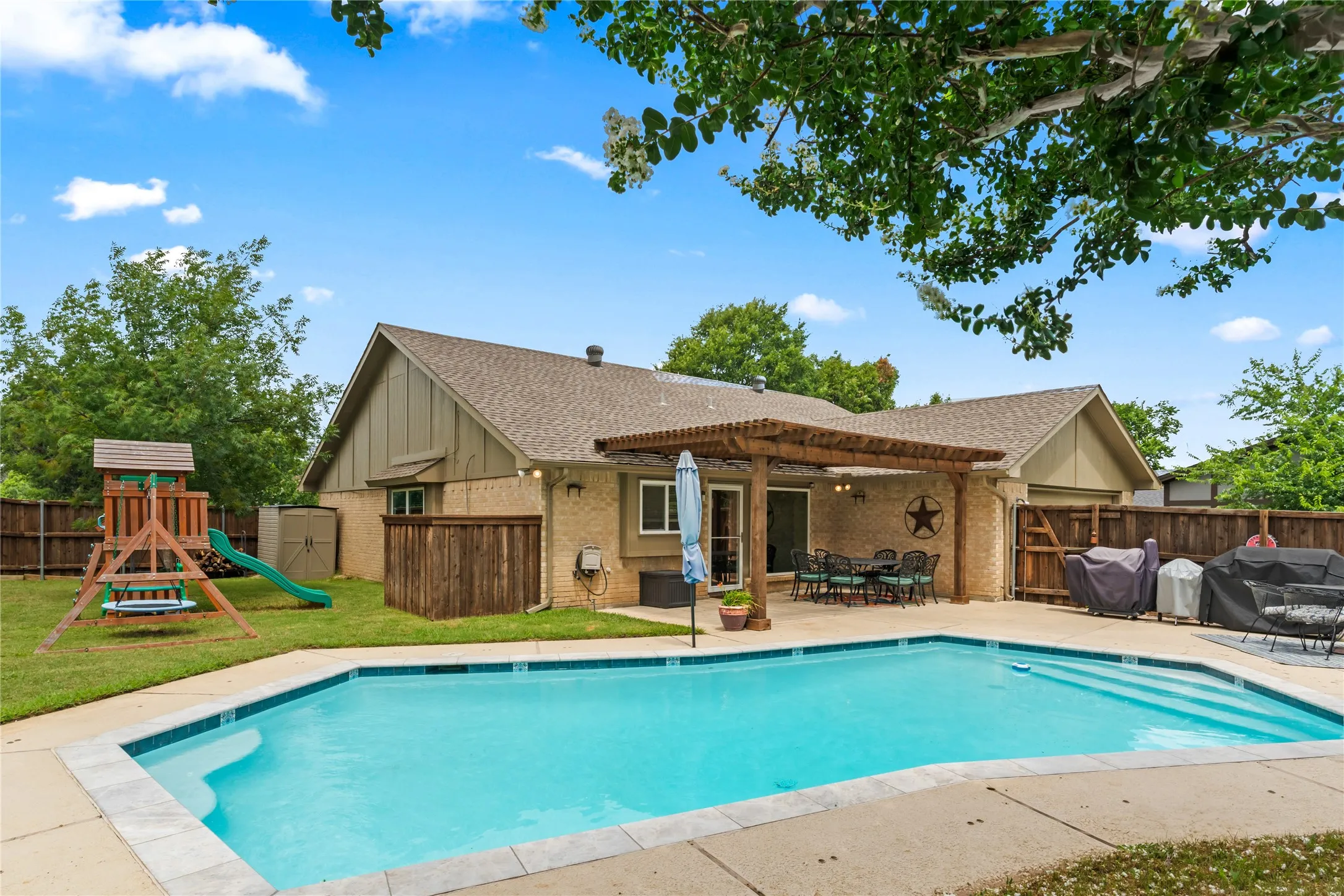 Backyard oasis featuring an in-ground swimming pool, patio, and a wood pergola
