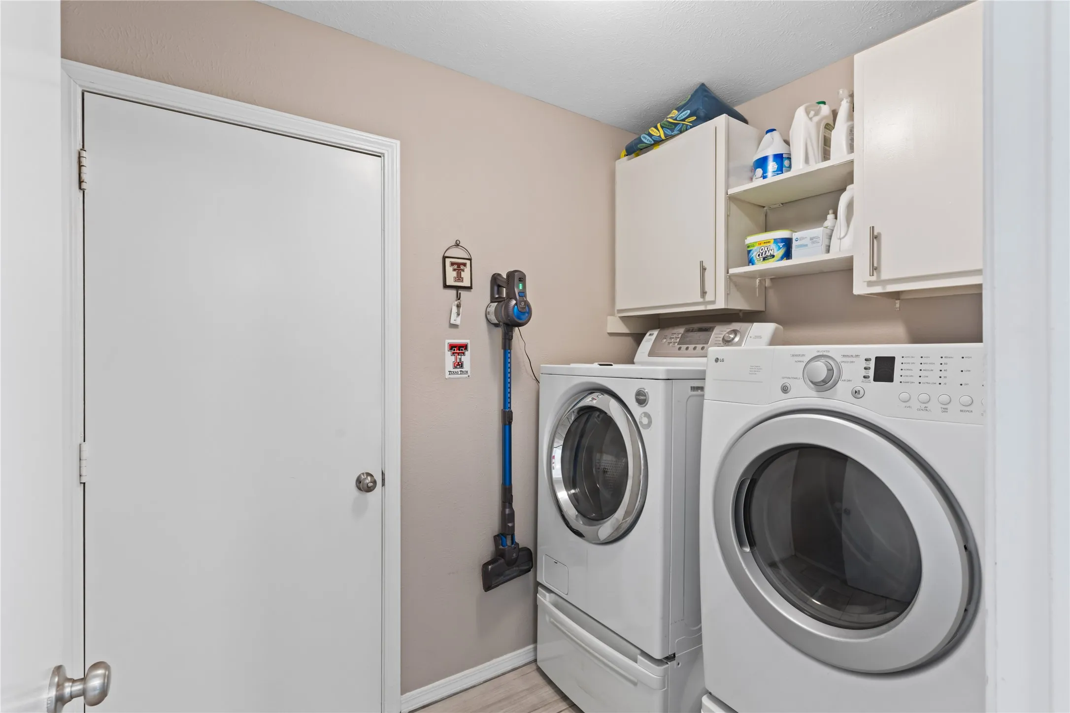 Integrated laundry area with upper cabinetry and open shelving