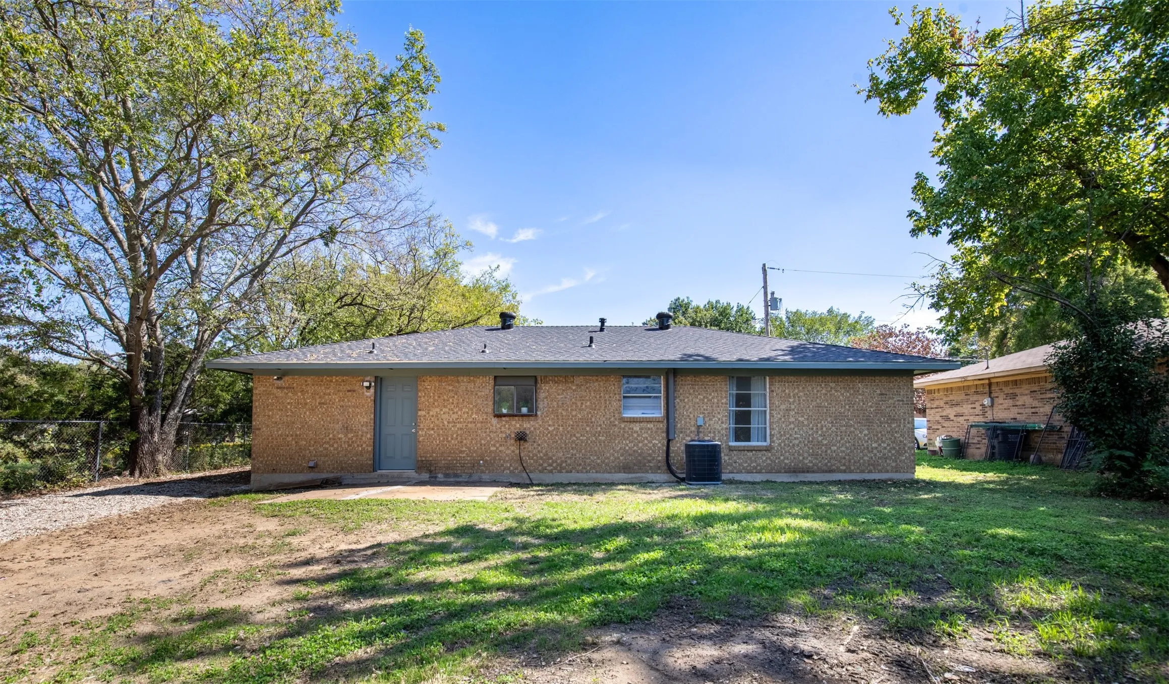 Backyard with concrete patio and door leading to garage.
