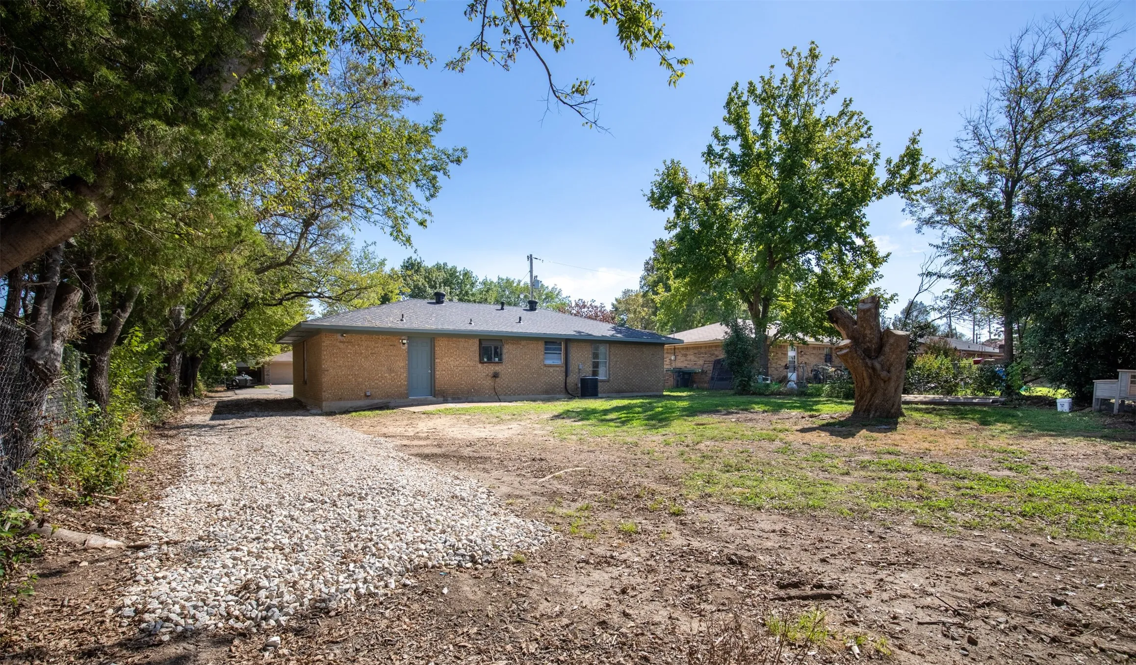 Expansive lot featuring a gravel driveway and mature trees.
