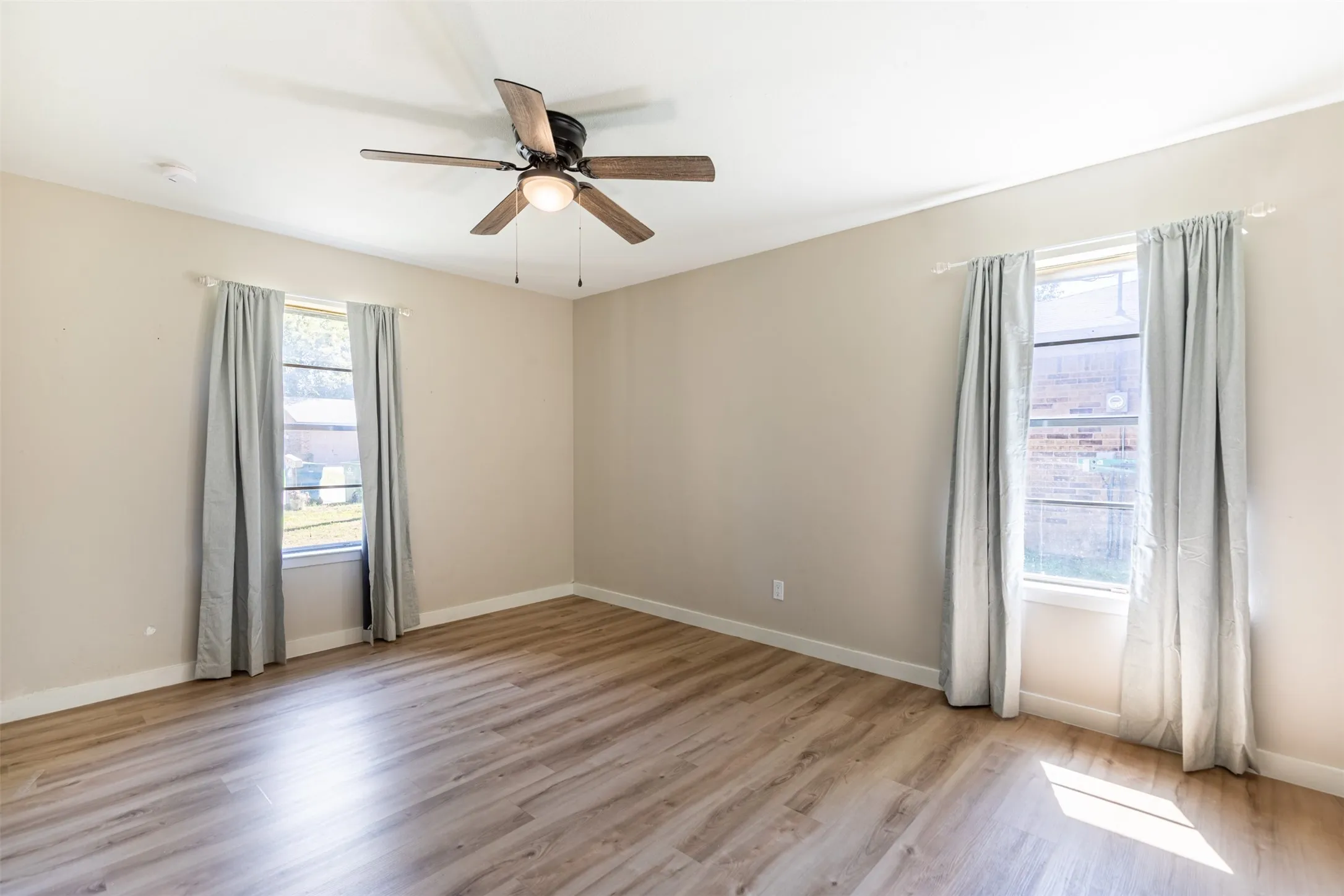 Bedroom features ceiling fan and two windows for natural light.