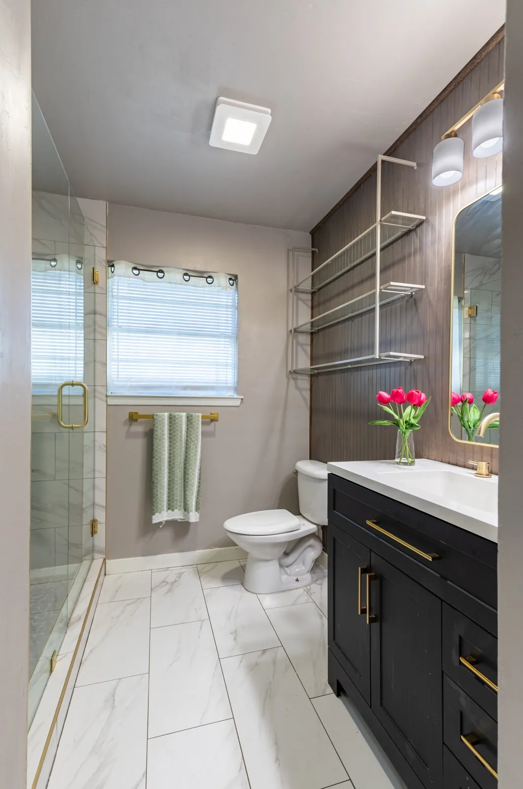 Renovated full bath with black modern cabinetry with golf finishes.