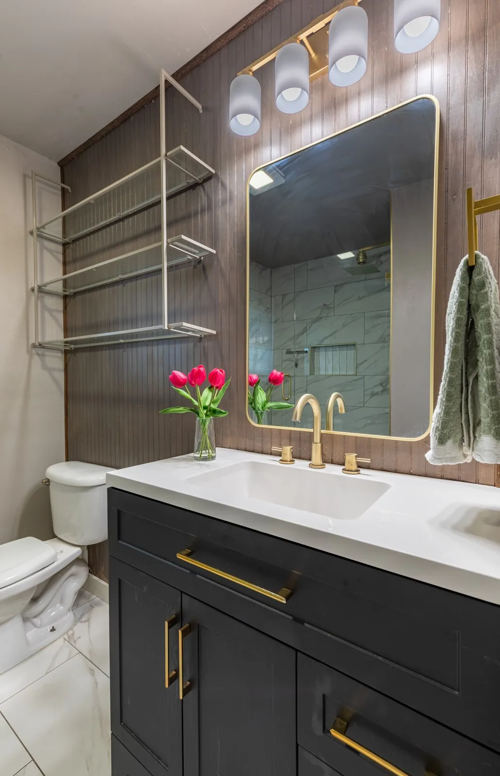 Full bath with shelving and framed gold mirror.