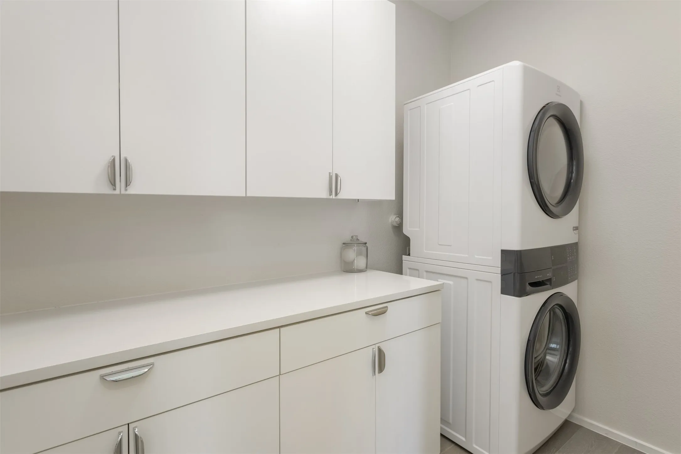 Laundry area with stacked washer / drying machine and cabinet space