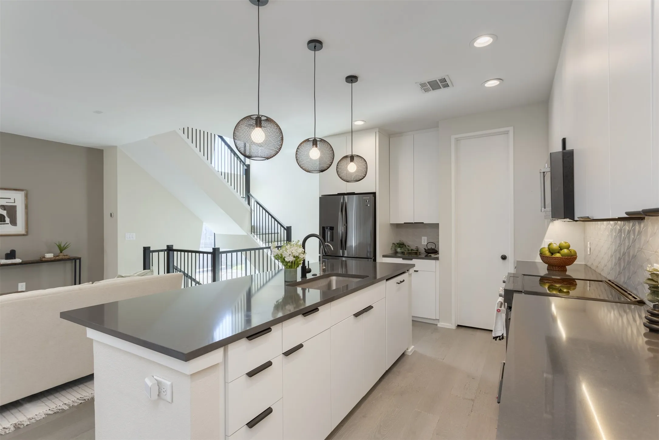Kitchen with white cabinets, a center island with sink, modern cabinets, and stainless steel refrigerator with ice dispenser
