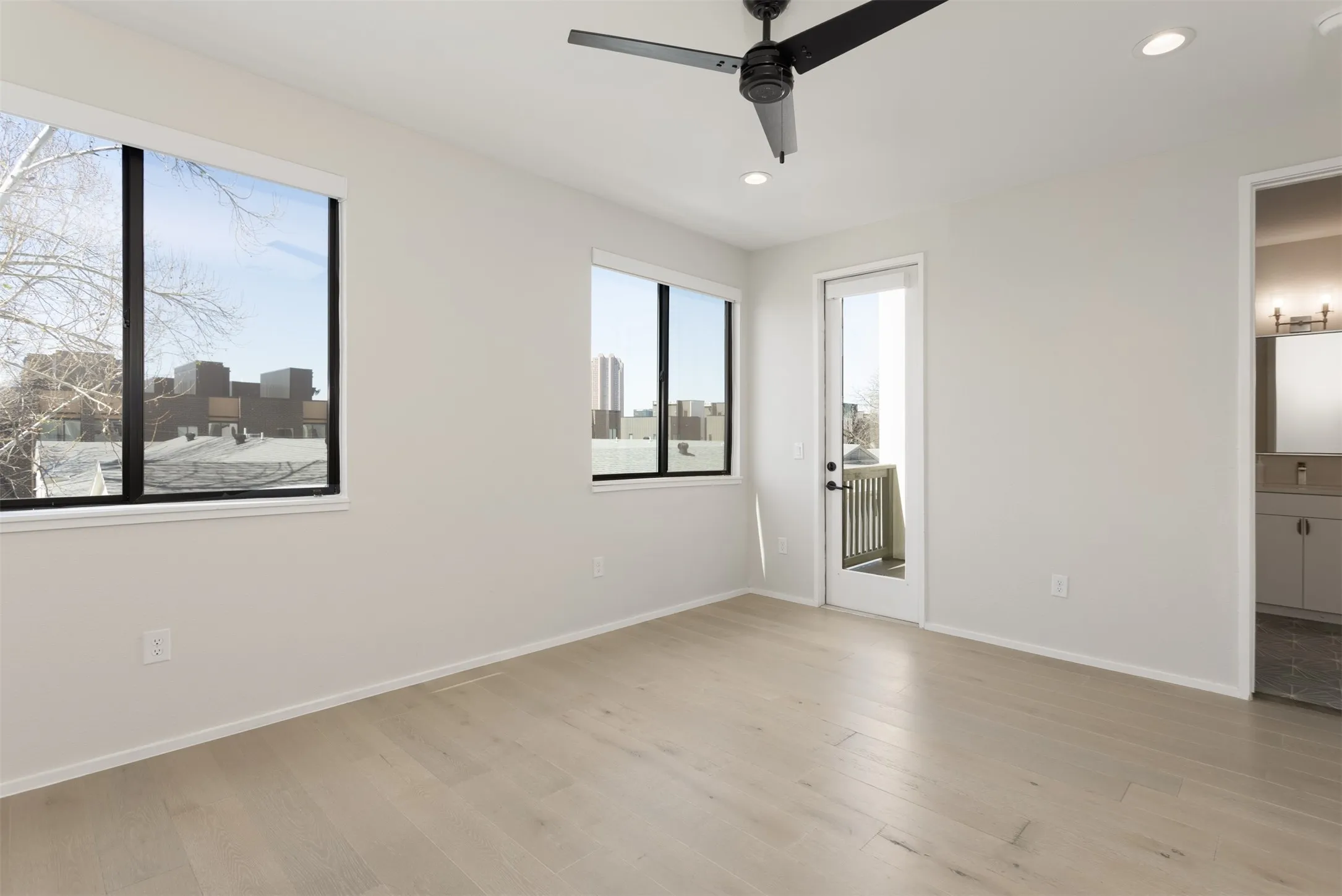 Unfurnished bedroom featuring light wood finished floors, recessed lighting, connected bathroom, ceiling fan, and access to outside