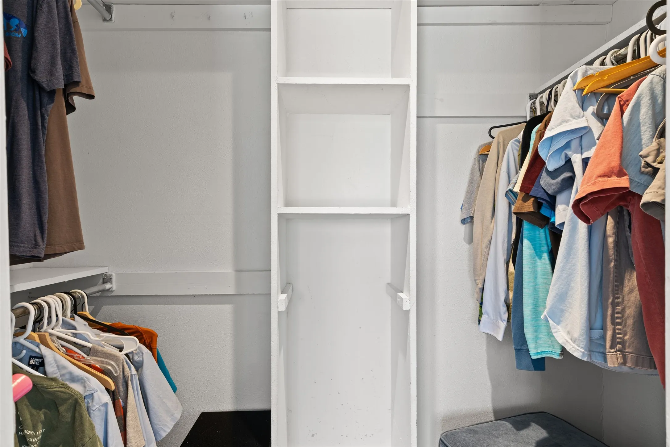 Built-in shelving unit with multiple compartments, dual clothing rods, and white painted finishes
