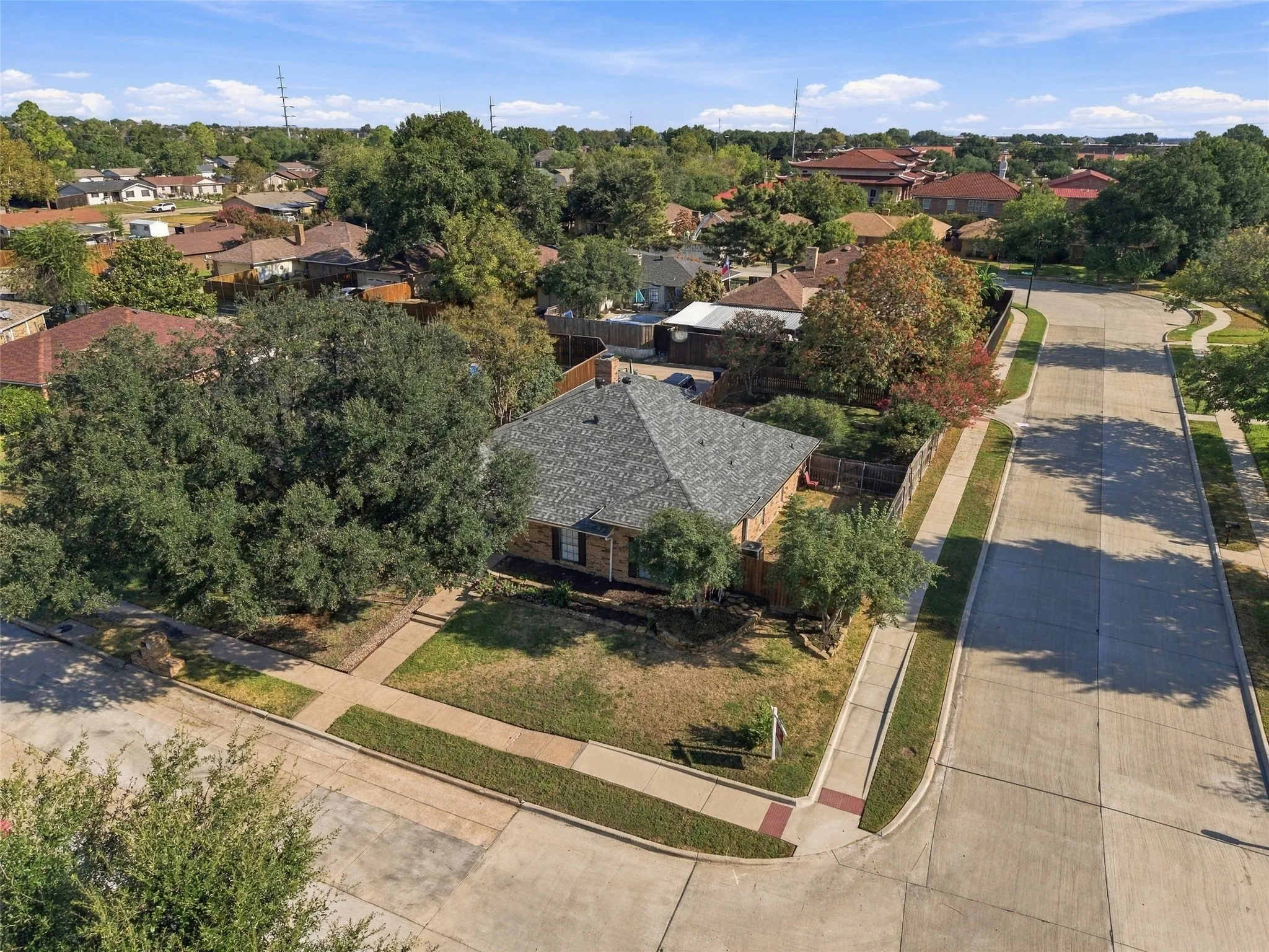 Corner lot with mature trees, established landscaping, and a fenced yard