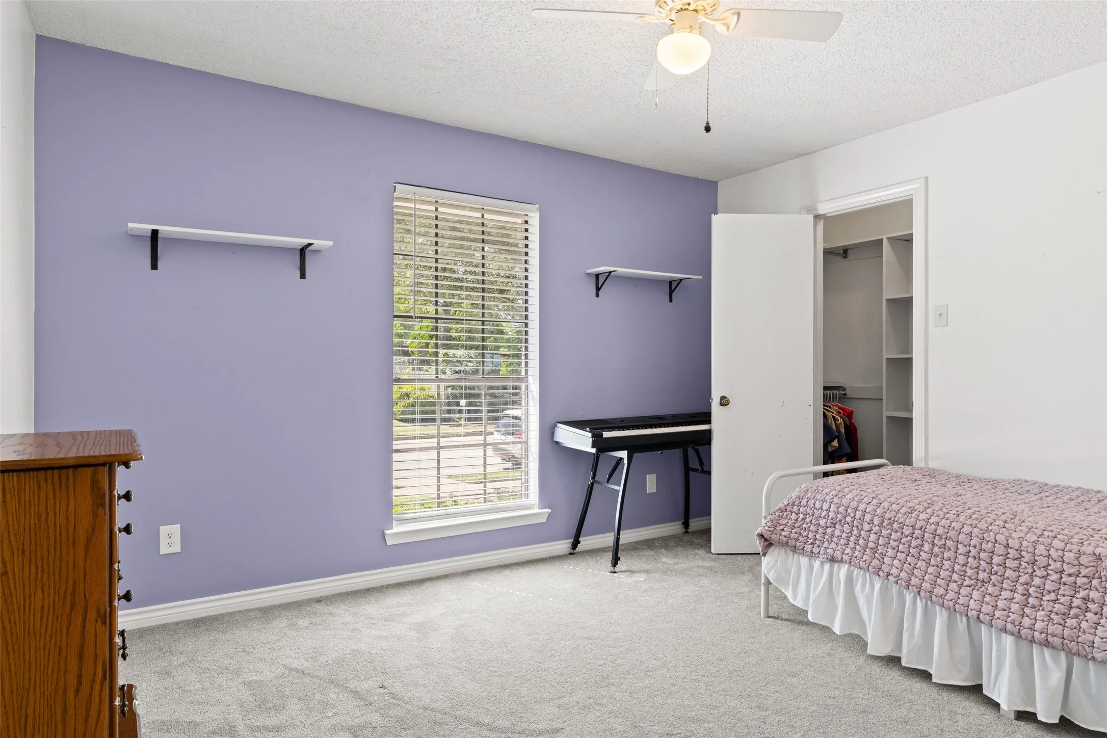 Recessed window with blinds, ceiling fan with light fixture, built-in shelving in closet, and neutral-toned carpeting