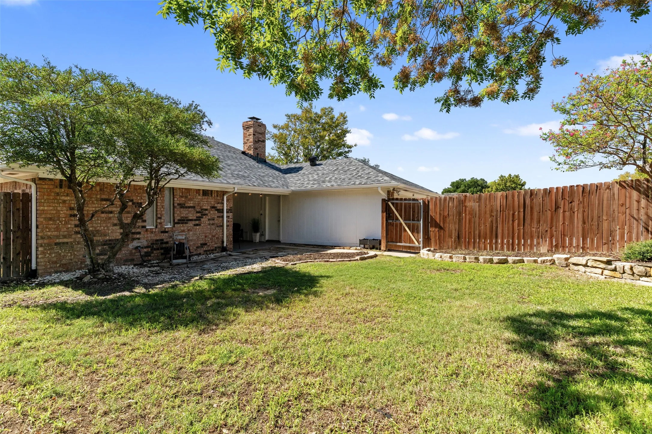 Expansive backyard with a manicured lawn, wood privacy fence, and stone retaining wall