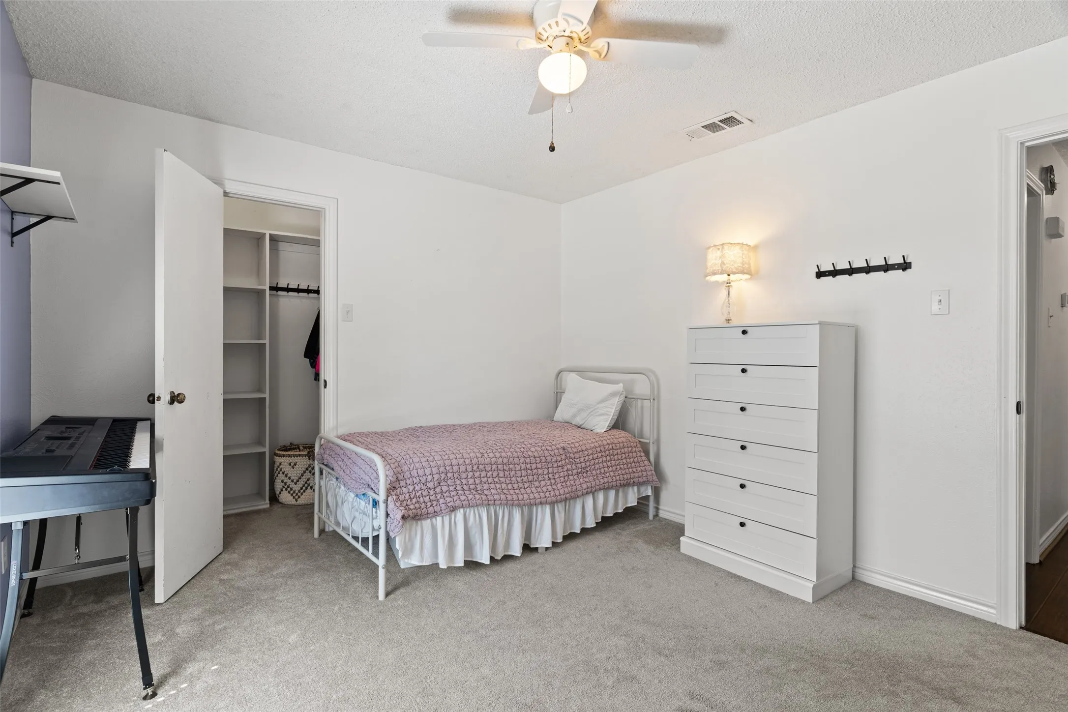 Spacious secondary bedroom featuring neutral carpeting, a ceiling fan with integrated lighting, white painted wood framing, and ample natural light