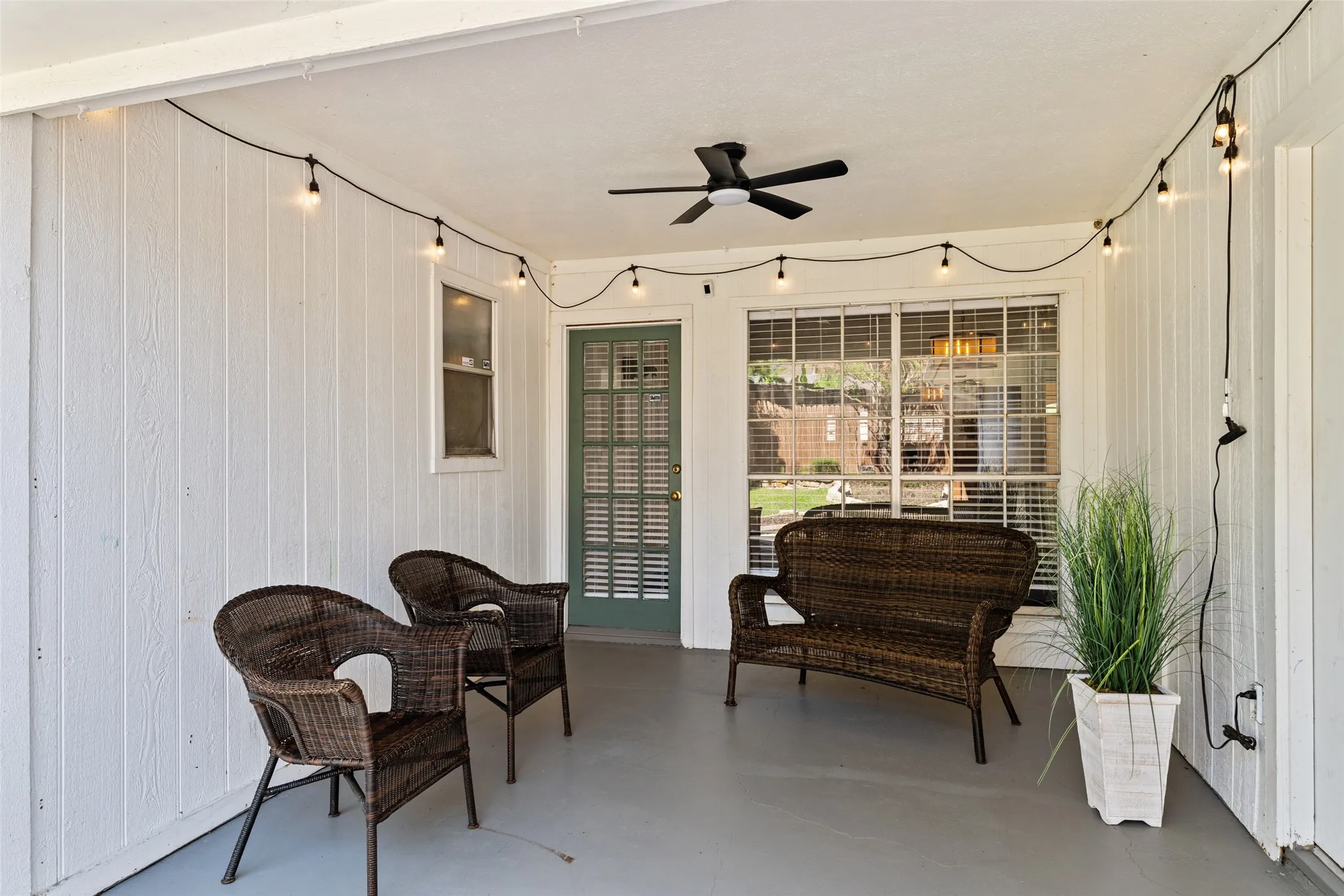 Covered patio featuring a ceiling fan, string lighting, and a sliding glass door