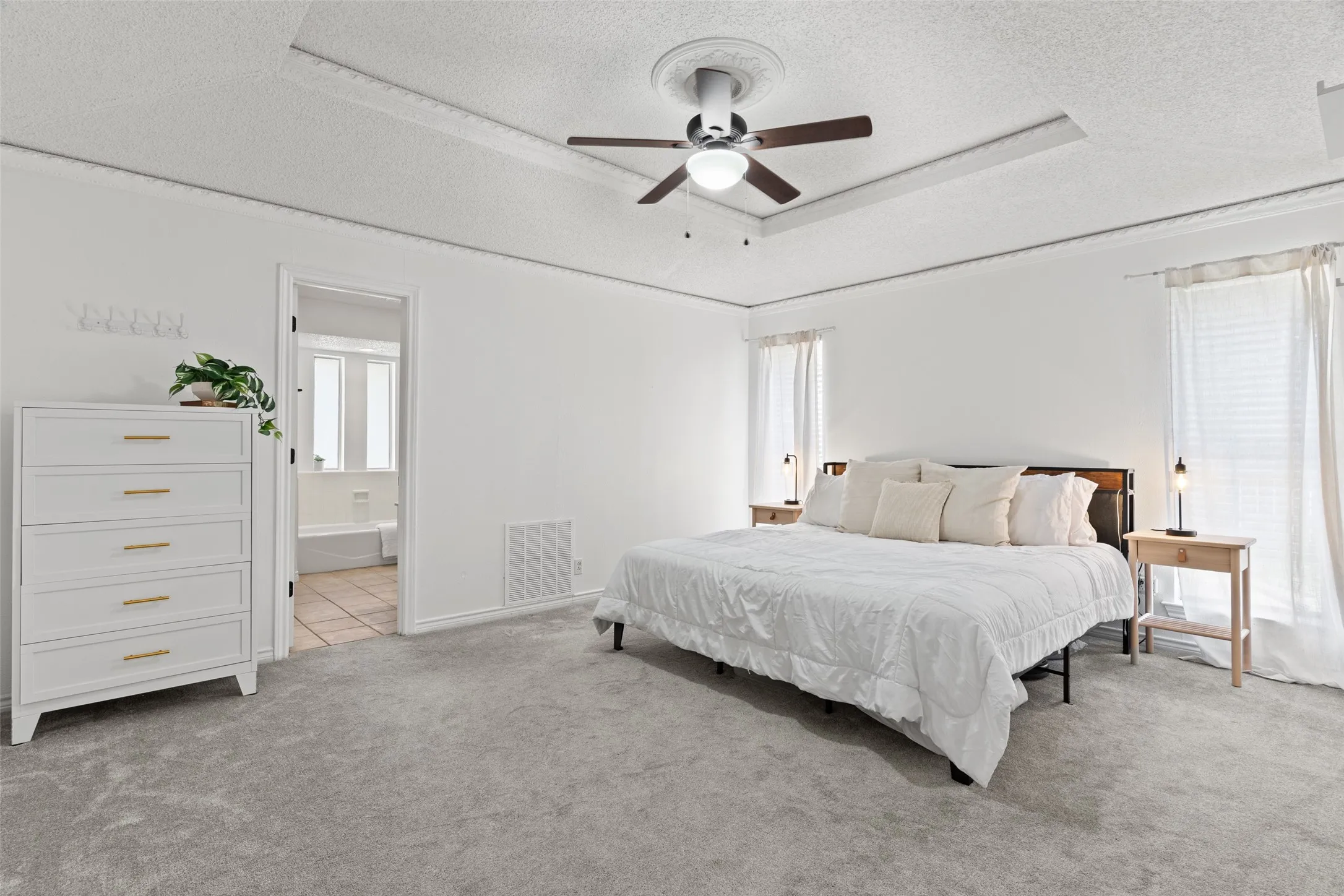 Recessed ceiling with an overhead fan, dual windows, and carpeted flooring