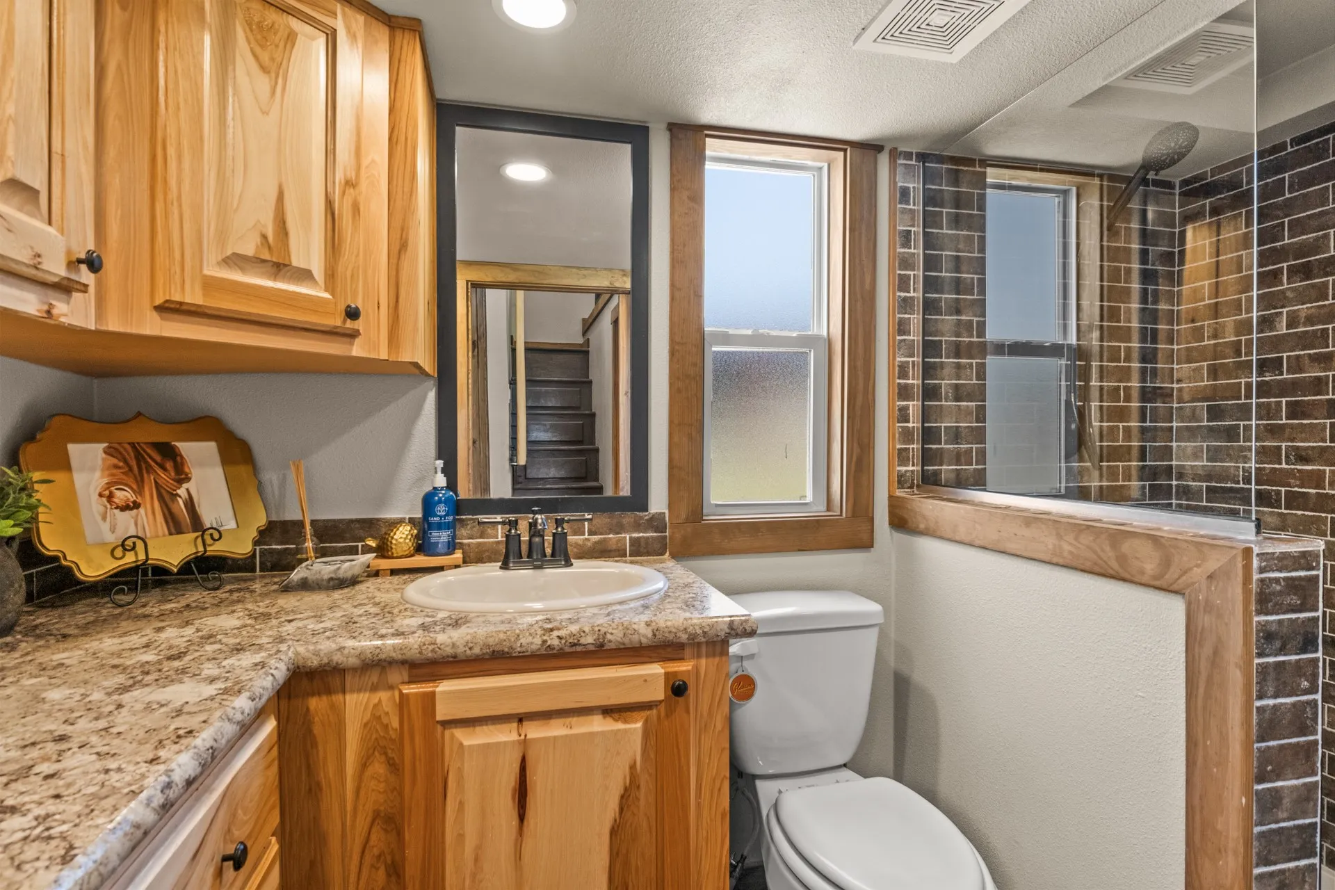 Full bathroom featuring vanity, tiled shower, and a textured ceiling