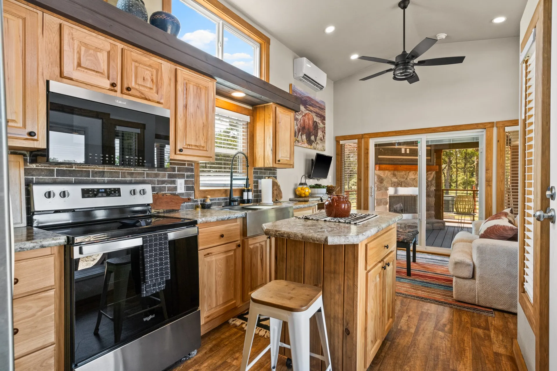 Kitchen featuring stainless steel electric range oven, black microwave, backsplash, dark wood finished floors, and a center island