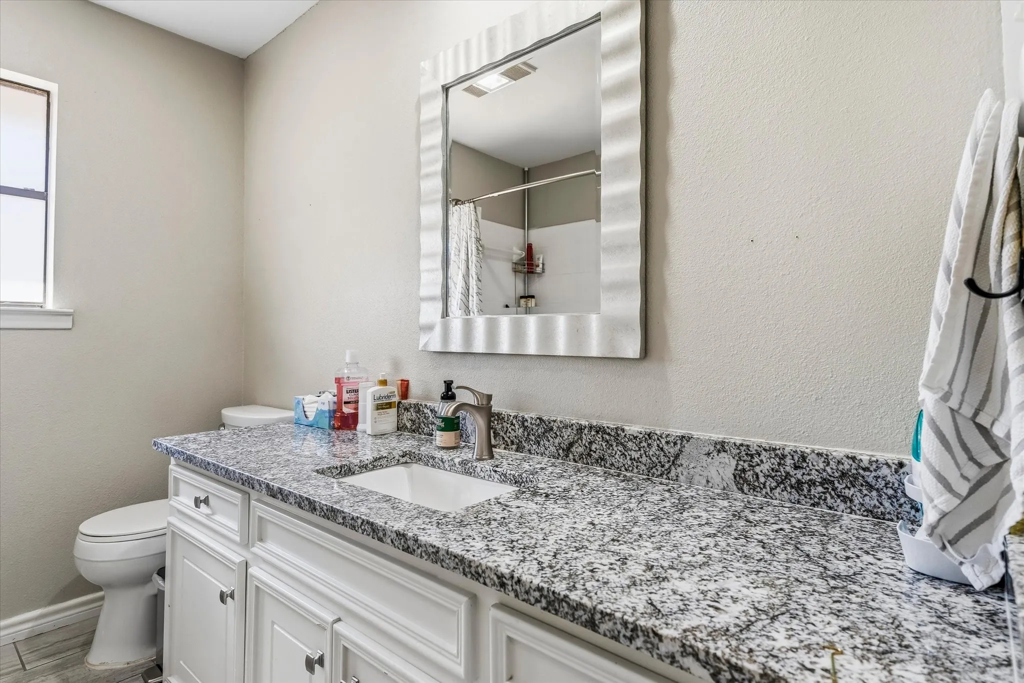 Vanity with a granite countertop, undermount sink, and a framed mirror