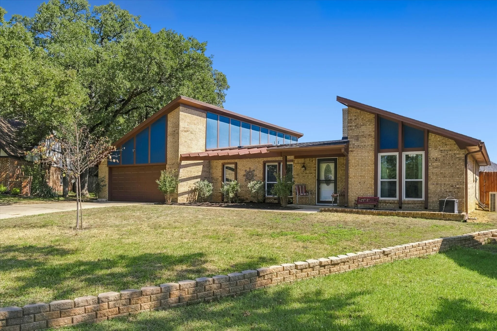 Brick exterior with a unique sloped roofline, attached garage, and prominent front entry