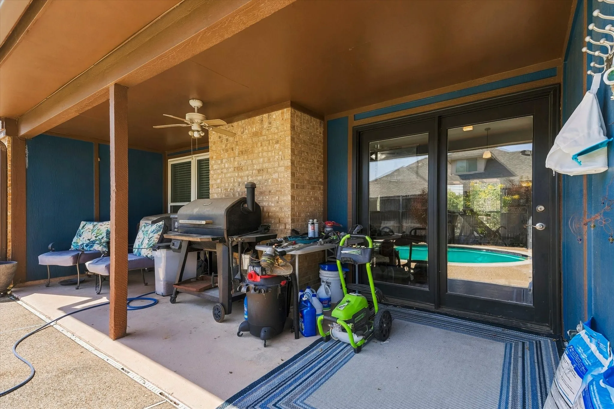 Covered patio featuring a ceiling fan, brick accent wall, and sliding glass doors