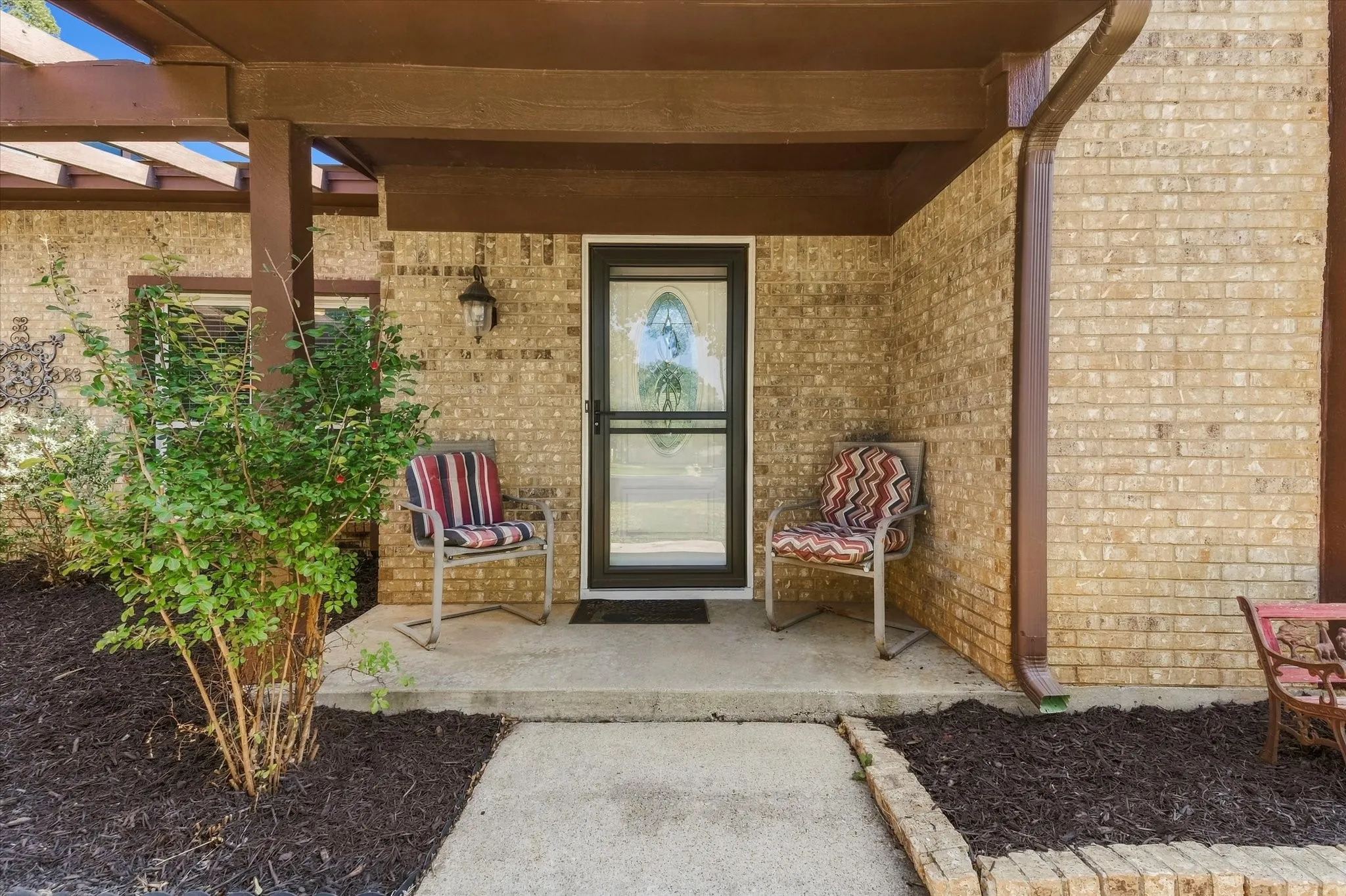 Brick exterior with covered entry, storm door, and exterior lighting